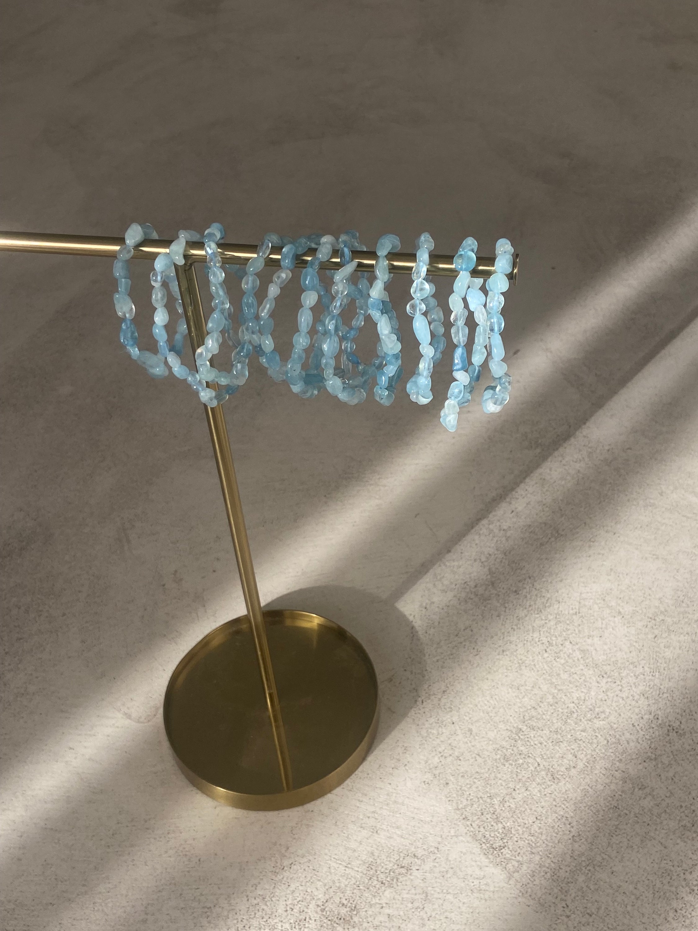 Bracelet galets en aigue marine, symbole de confiance en soi et d'équilibre énergétique, présenté sur un fond neutre.