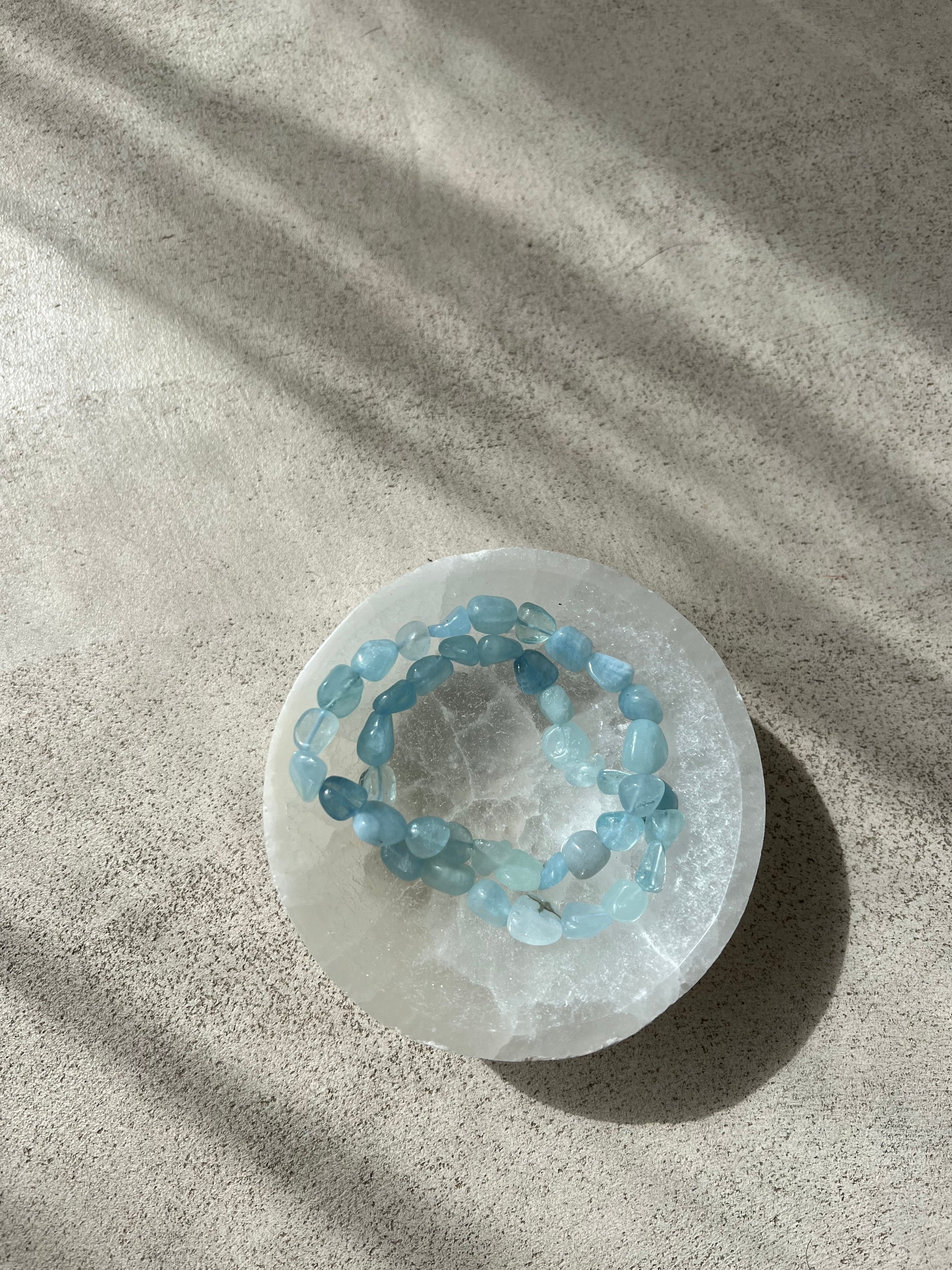 Bracelet galets en aigue marine, symbole de confiance en soi et d'équilibre énergétique, présenté sur un fond neutre.