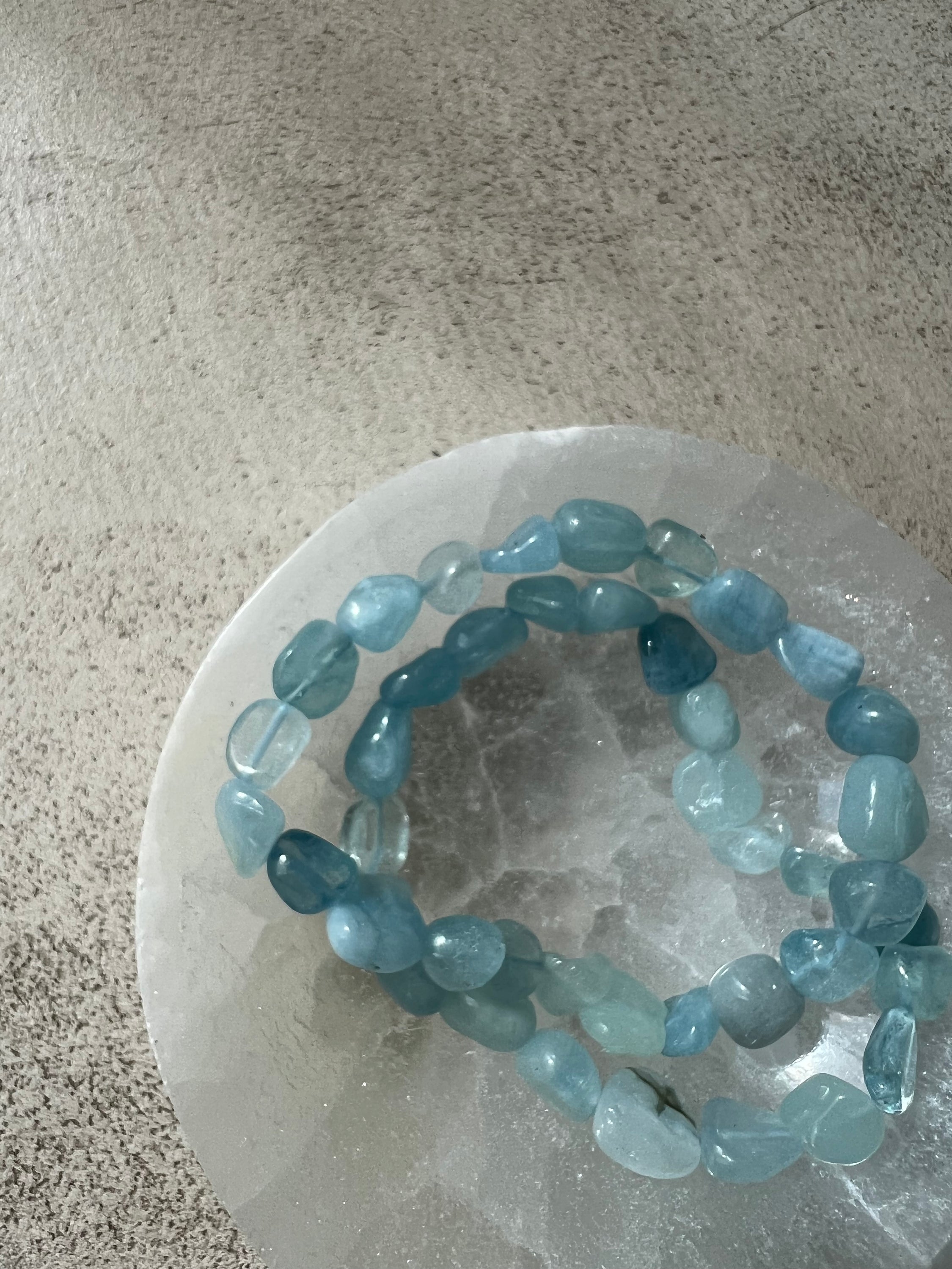 Bracelet galets en aigue marine, symbole de confiance en soi et d'équilibre énergétique, présenté sur un fond neutre.