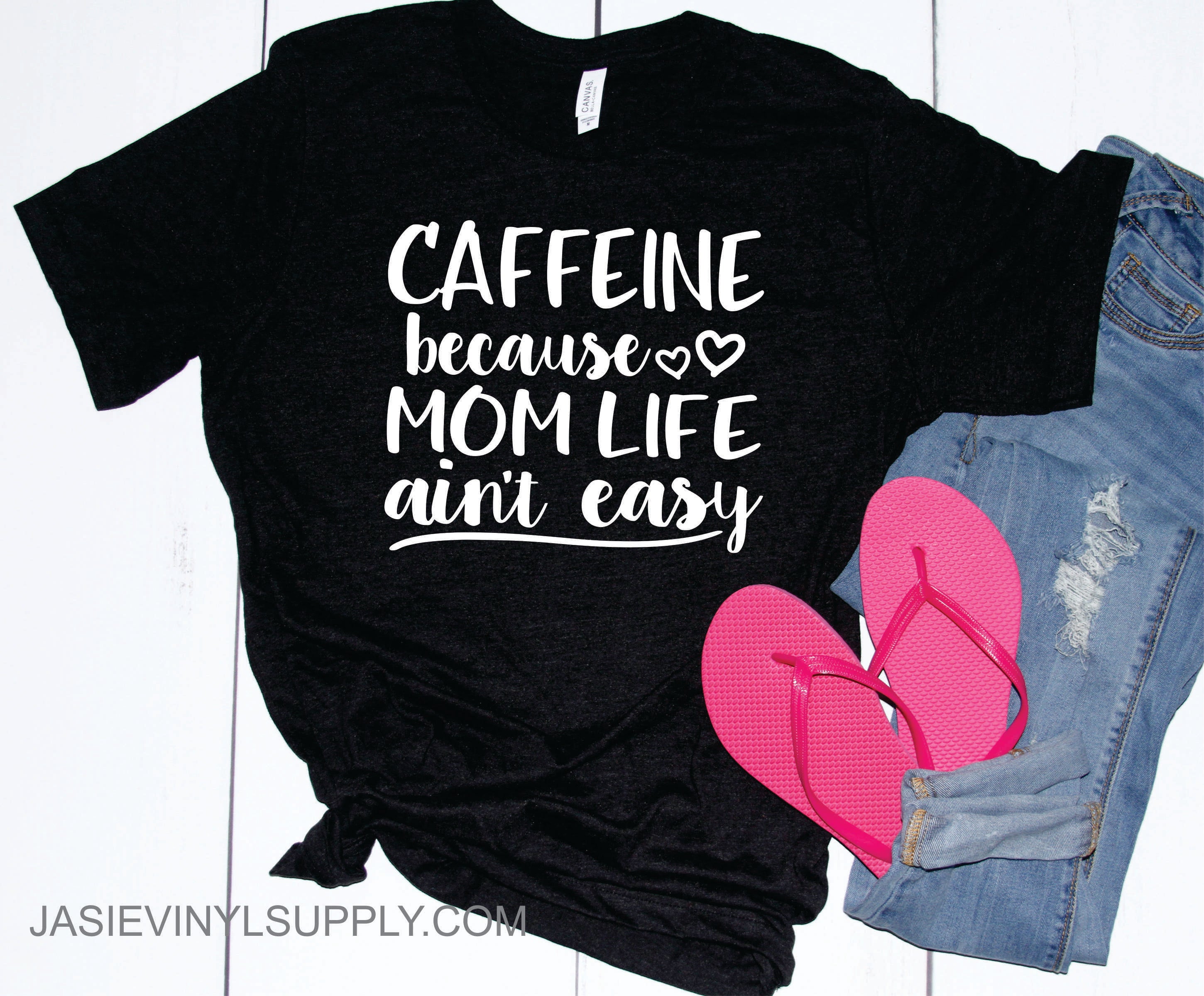 Caffeine Because Mom Life Ain't Easy Graphic Tee displayed on a hanger, showcasing its soft fabric and fun design.