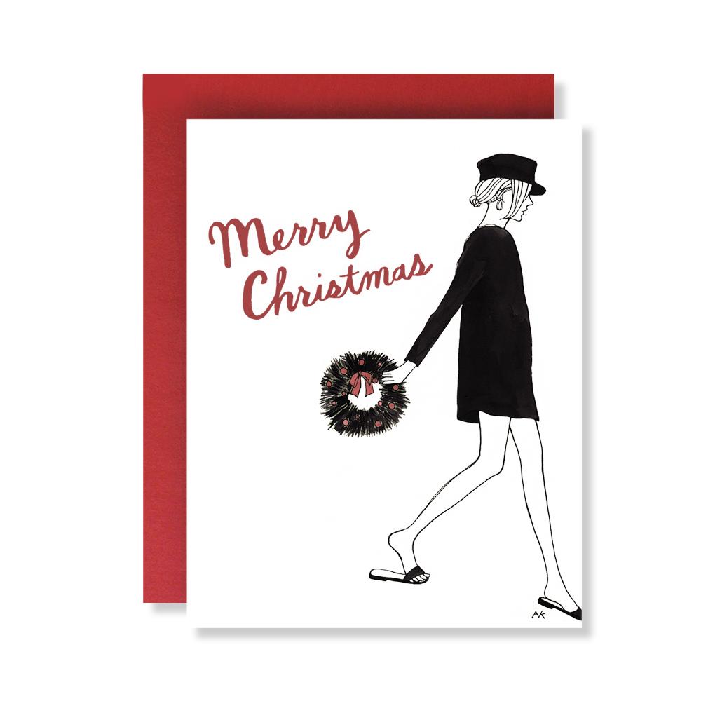 A beautifully illustrated Christmas card featuring a festive wreath design, accompanied by a shiny red metallic envelope.