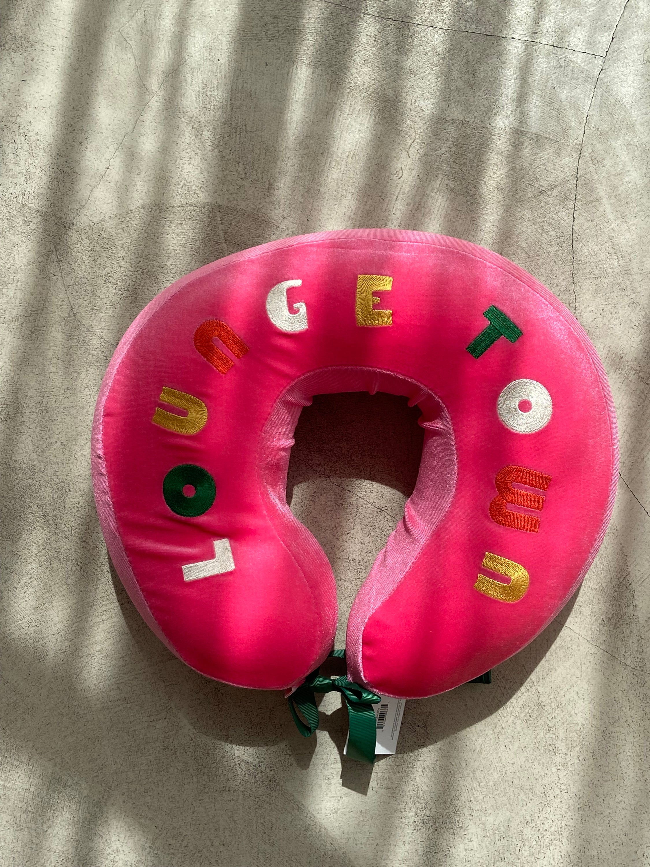 COUSSIN DE VOYAGE travel pillow in pink and yellow, featuring a soft removable cover and satin cord for easy attachment to luggage.