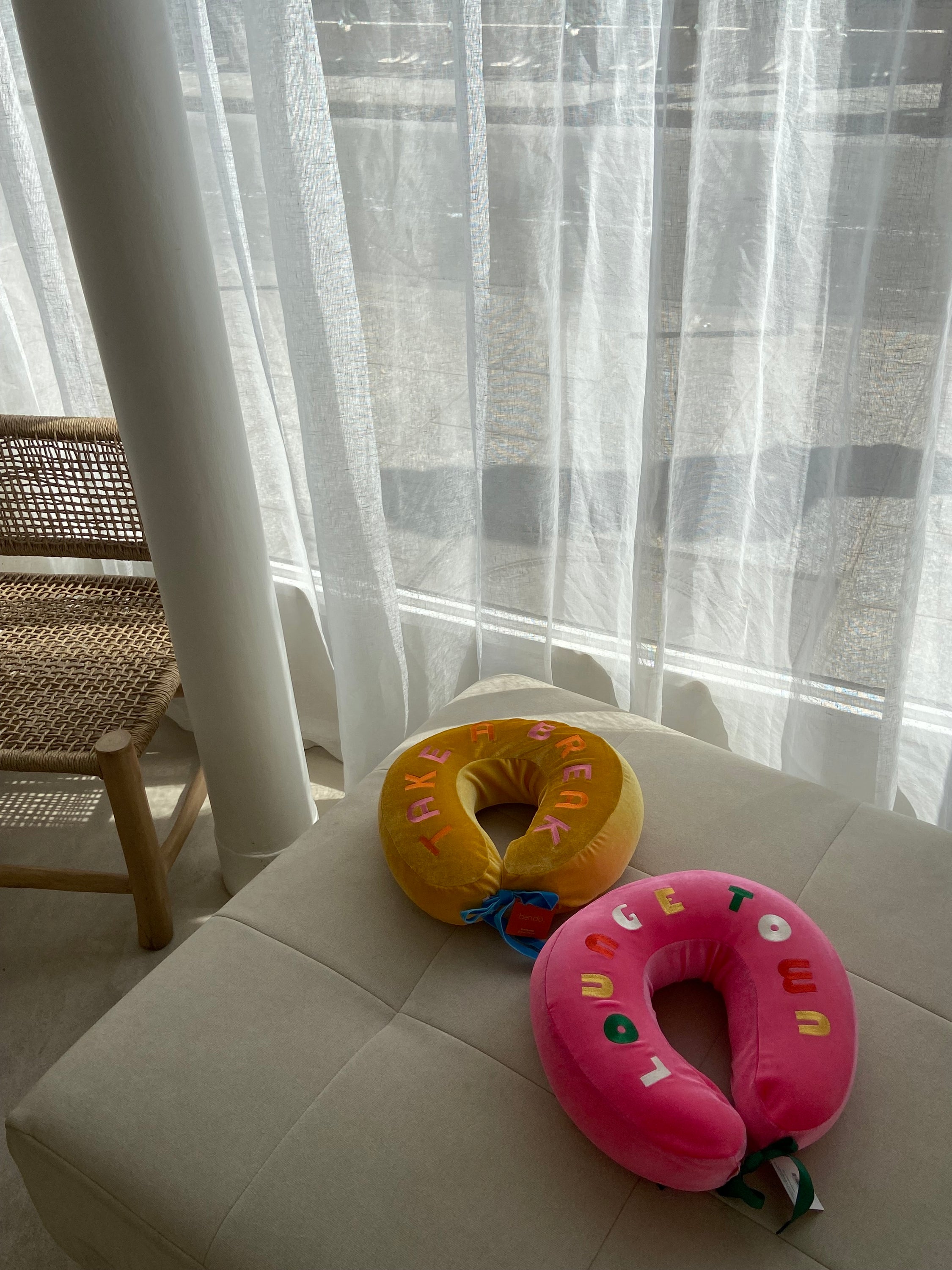 COUSSIN DE VOYAGE travel pillow in pink and yellow, featuring a soft removable cover and satin cord for easy attachment to luggage.