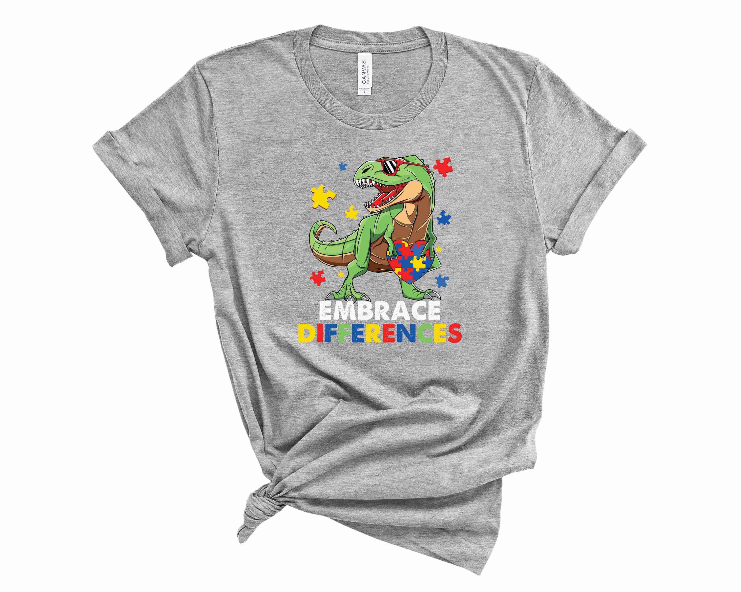 Dino Embrace Difference Graphic Tee featuring a colorful dinosaur design on a unisex t-shirt.