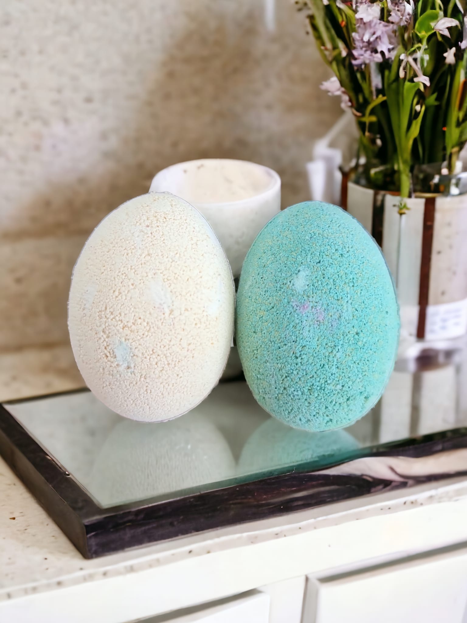 Two vibrant egg-shaped bath bombs in yellow and green, packaged in a Kraft bag with an open window, showcasing their delightful colors.