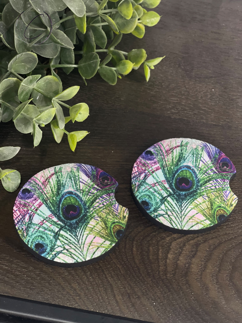 A set of Glitter Peacock Feathers car coasters featuring a vibrant peacock feather design, made of durable neoprene material.