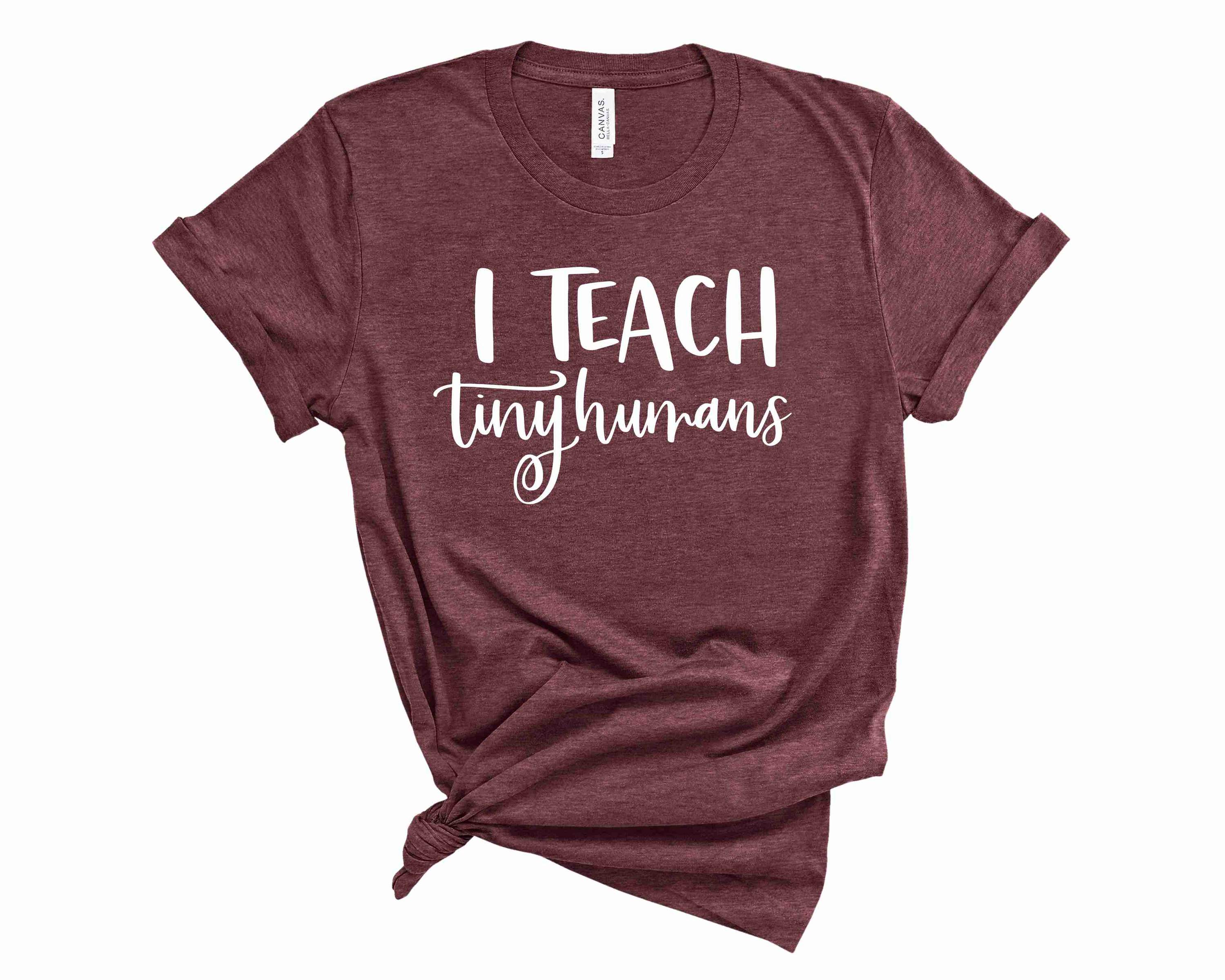 A unisex graphic tee featuring the phrase 'I Teach Tiny Humans' in bold letters, showcasing a playful design suitable for educators and parents.