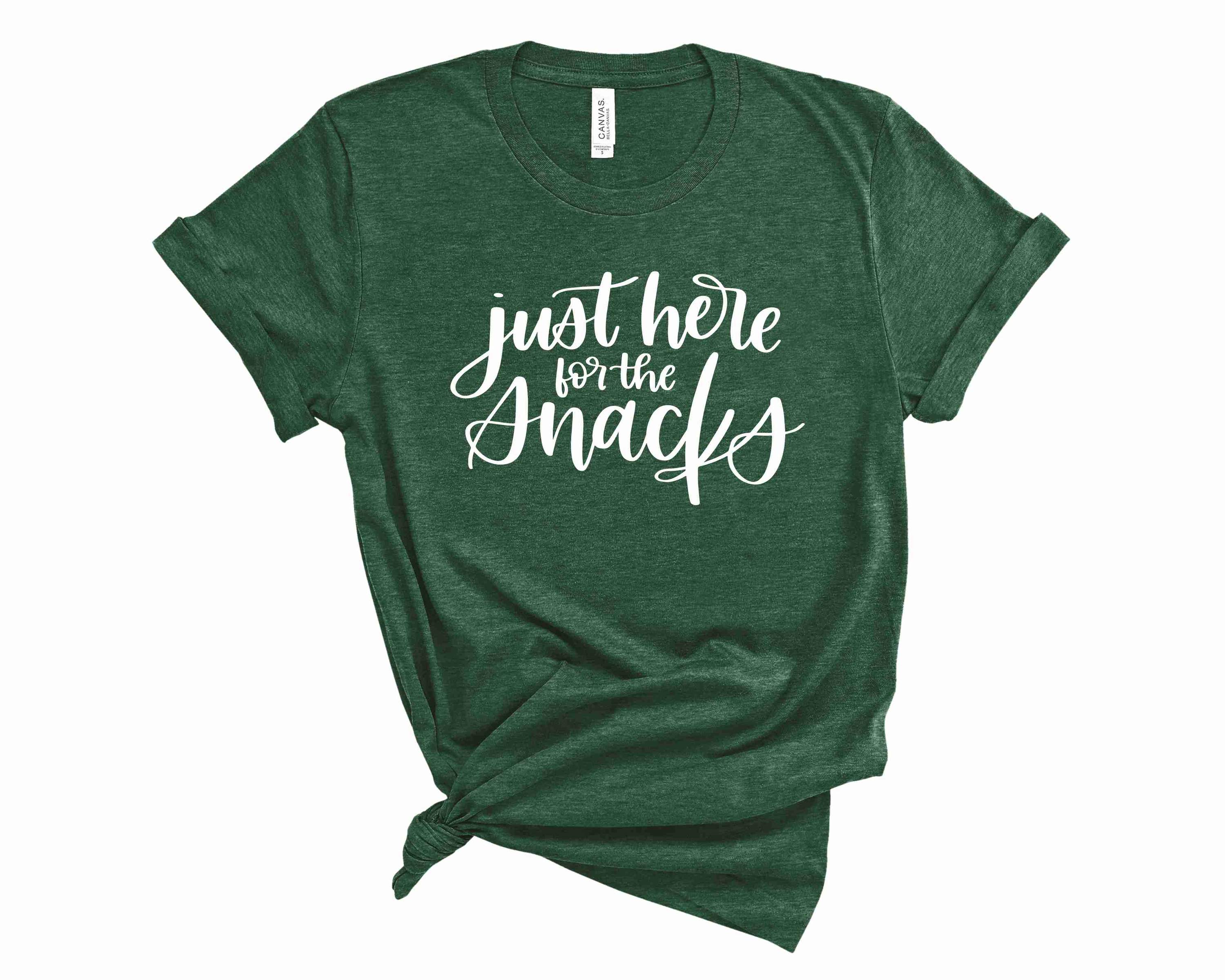 A unisex graphic tee featuring the phrase 'Just Here for the Snacks' in bold, colorful lettering, perfect for snack lovers.