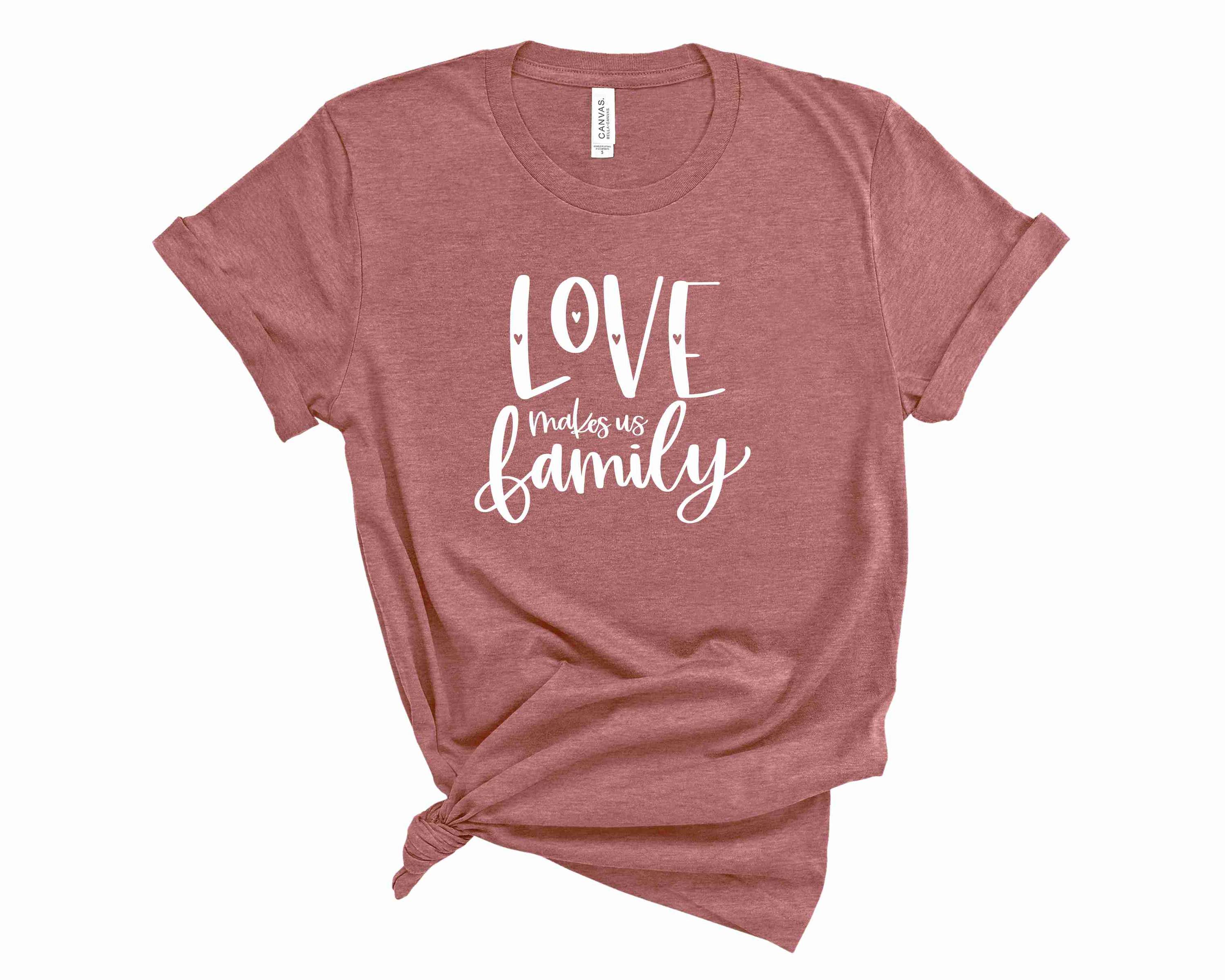 A unisex graphic tee featuring the phrase 'Love makes us family' in vibrant colors, perfect for casual wear.