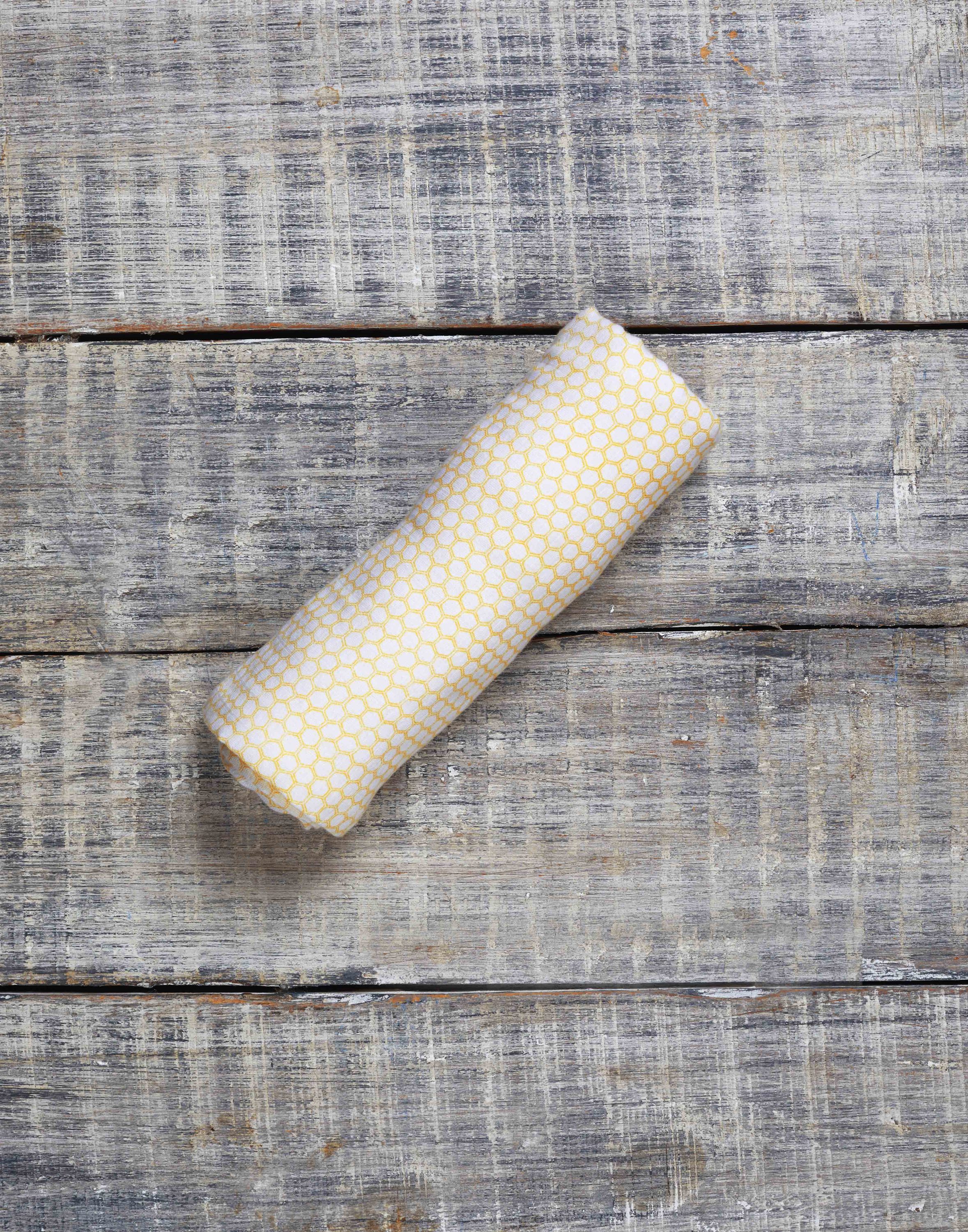 A soft and breathable organic cotton swaddle in a stylish hive pattern, perfect for wrapping babies comfortably.