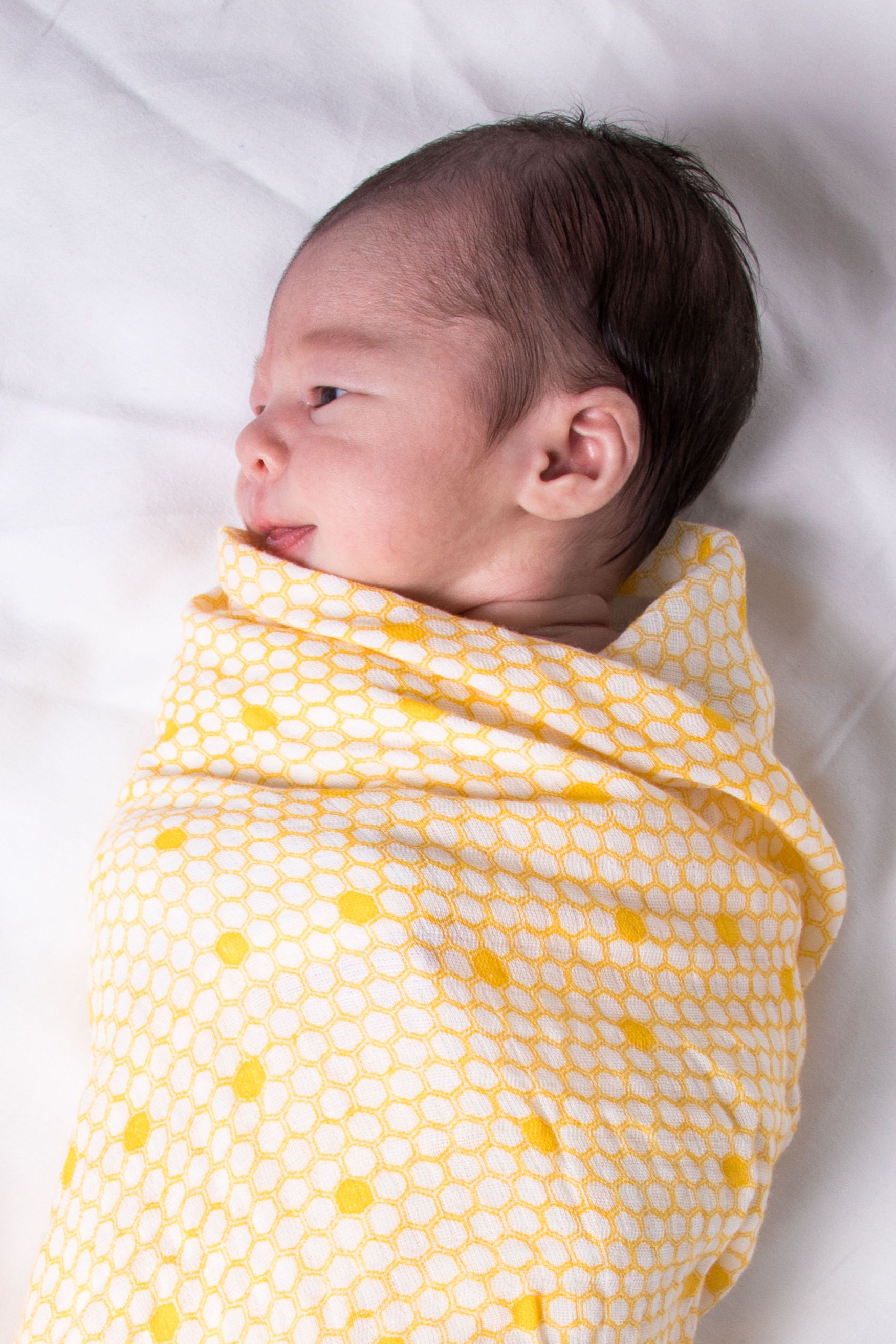 A soft and breathable organic cotton swaddle in a stylish hive pattern, perfect for wrapping babies comfortably.