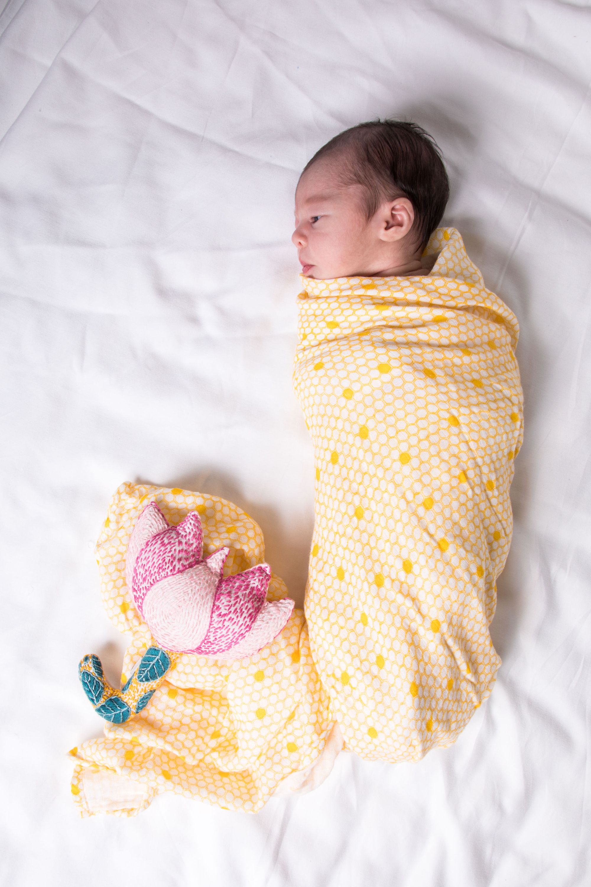 A soft and breathable organic cotton swaddle in a stylish hive pattern, perfect for wrapping babies comfortably.
