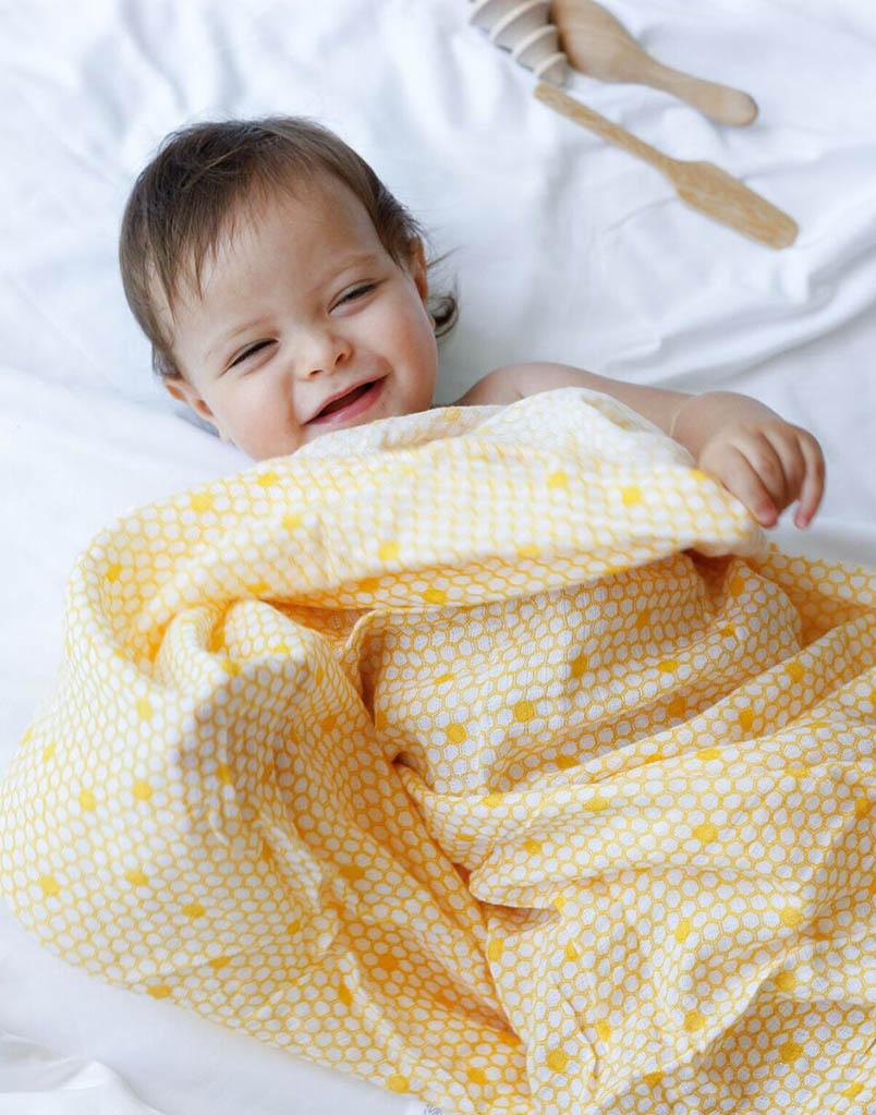 A soft and breathable organic cotton swaddle in a stylish hive pattern, perfect for wrapping babies comfortably.