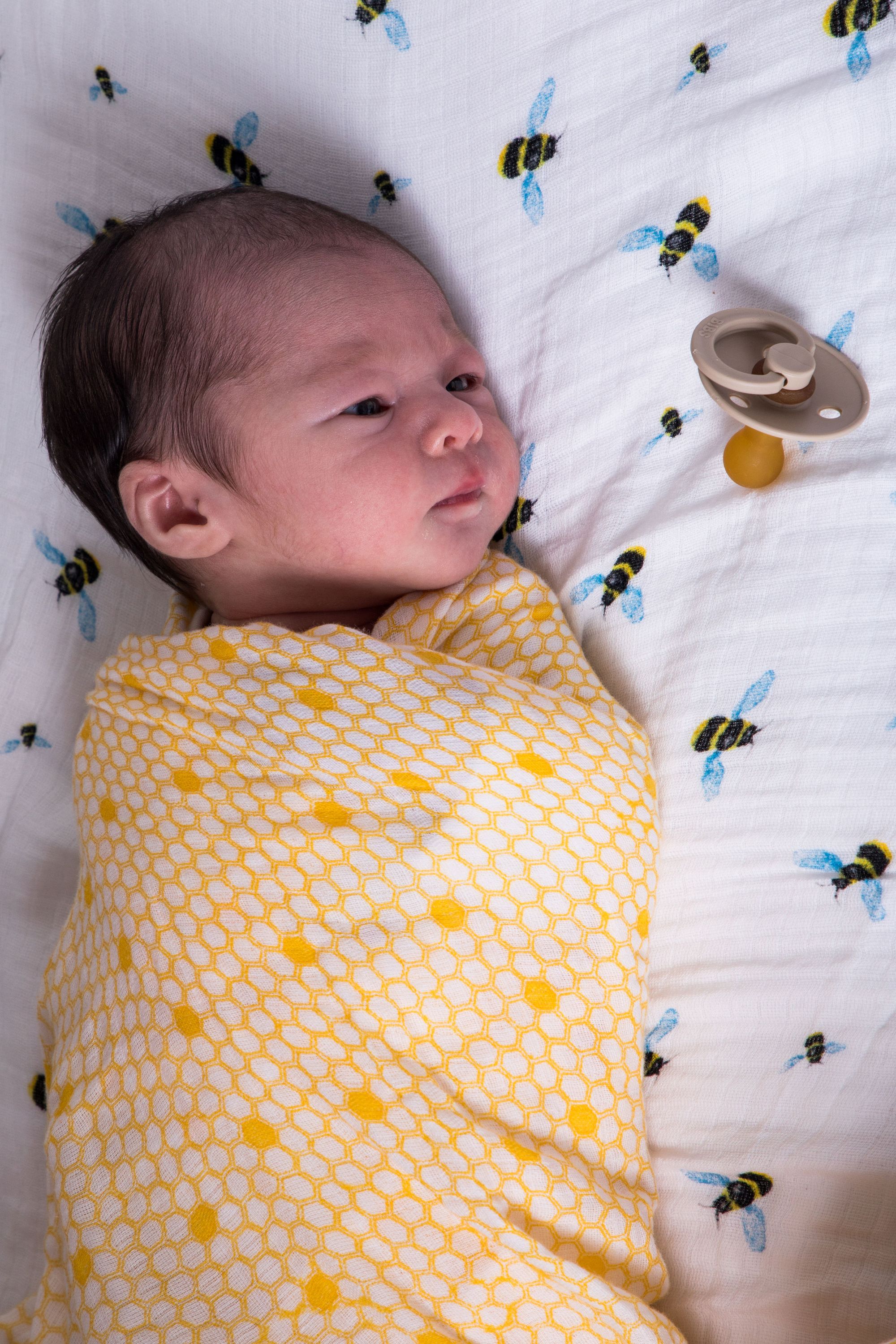 A soft and breathable organic cotton swaddle in a stylish hive pattern, perfect for wrapping babies comfortably.