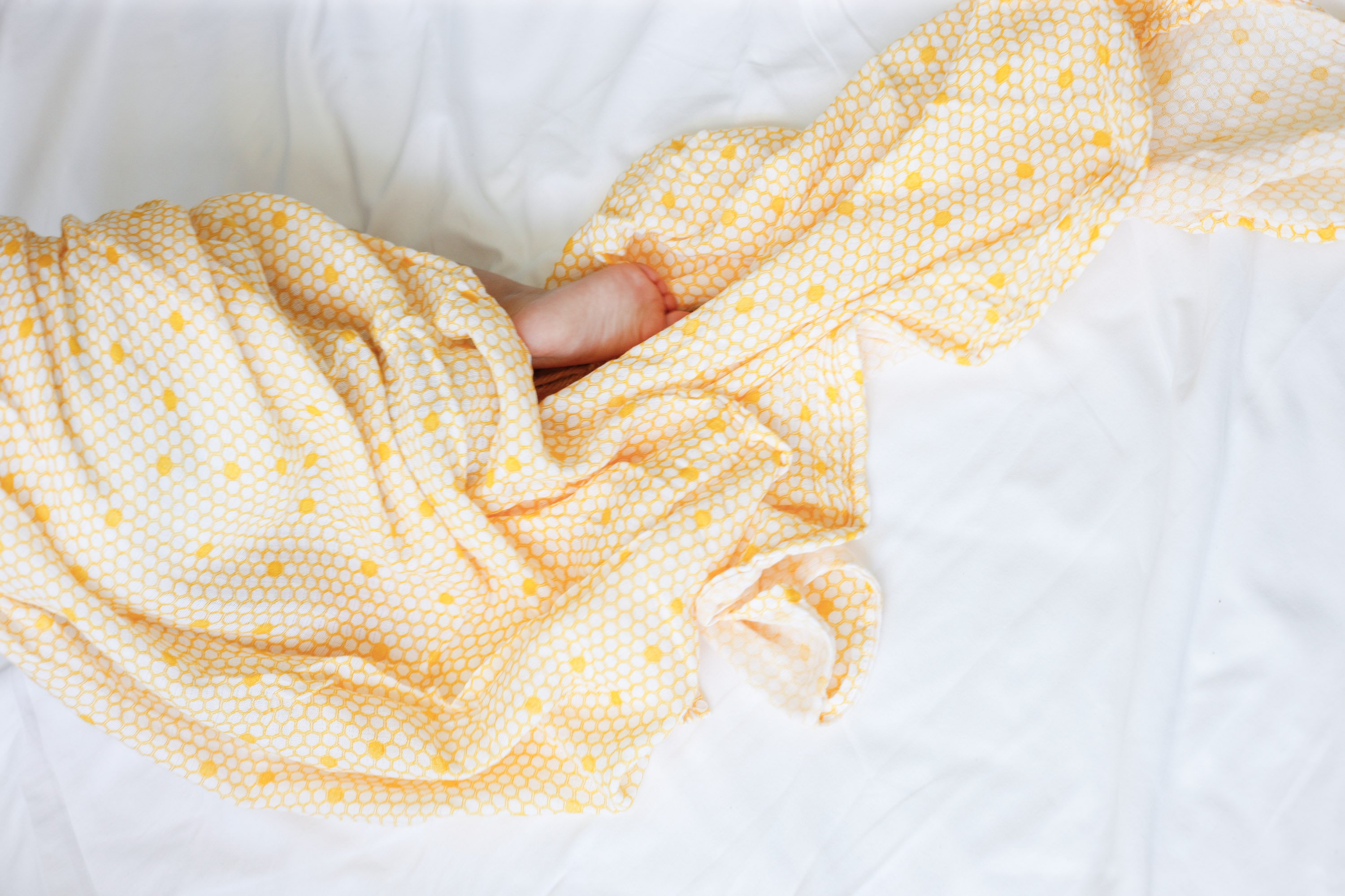 A soft and breathable organic cotton swaddle in a stylish hive pattern, perfect for wrapping babies comfortably.