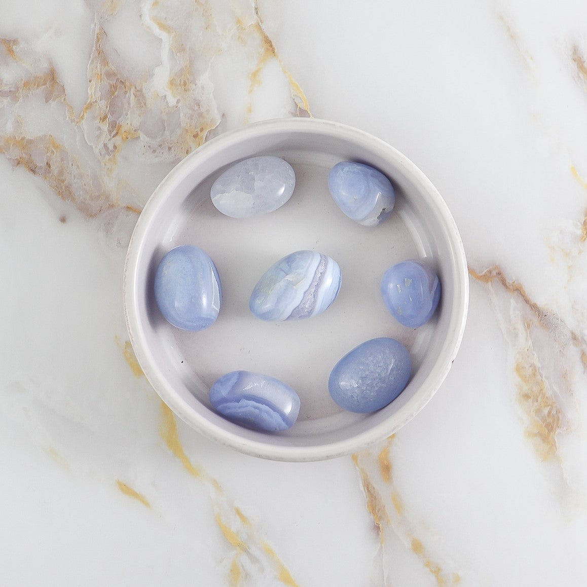 Pierre roulée en Calcédoine Blue Lace, présentant des motifs délicats et une couleur bleu clair apaisante.