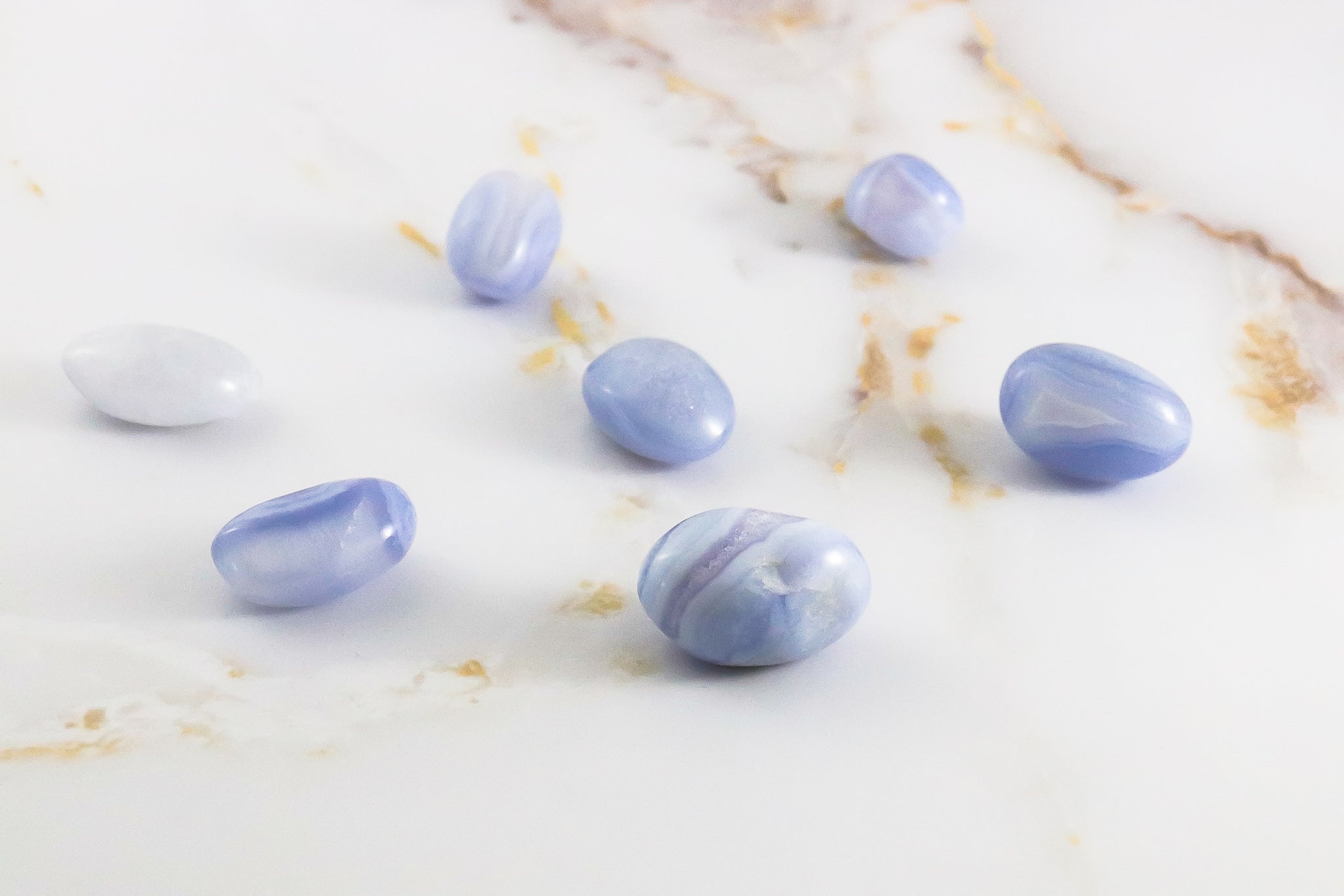 Pierre roulée en Calcédoine Blue Lace, présentant des motifs délicats et une couleur bleu clair apaisante.