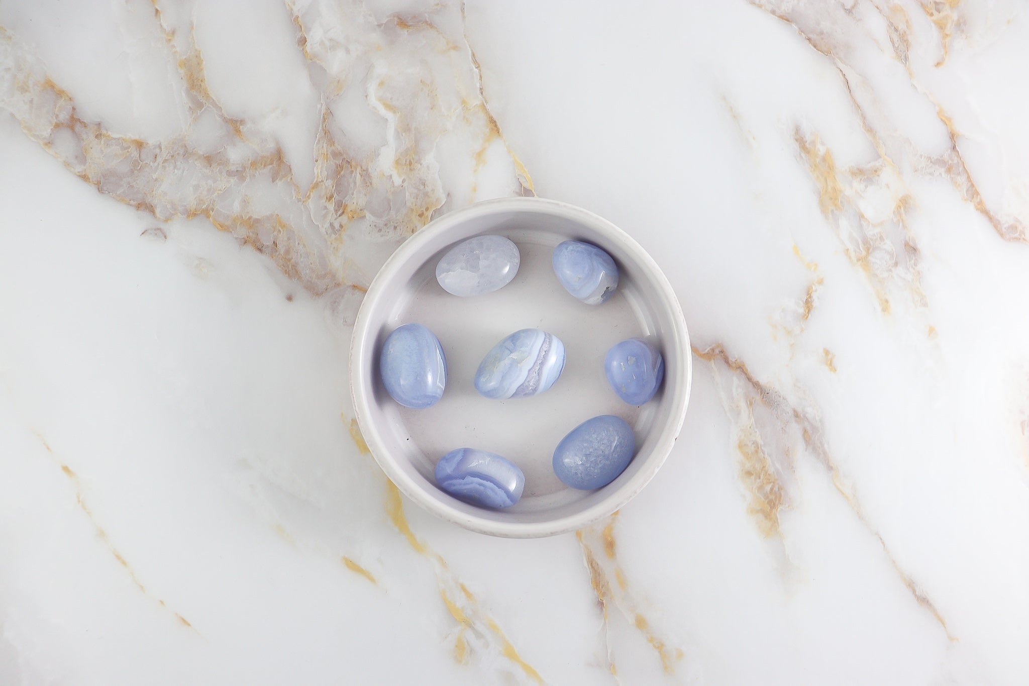 Pierre roulée en Calcédoine Blue Lace, présentant des motifs délicats et une couleur bleu clair apaisante.