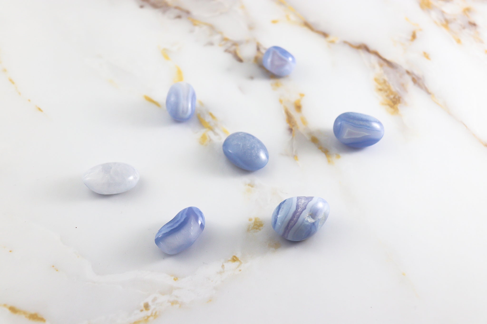 Pierre roulée en Calcédoine Blue Lace, présentant des motifs délicats et une couleur bleu clair apaisante.