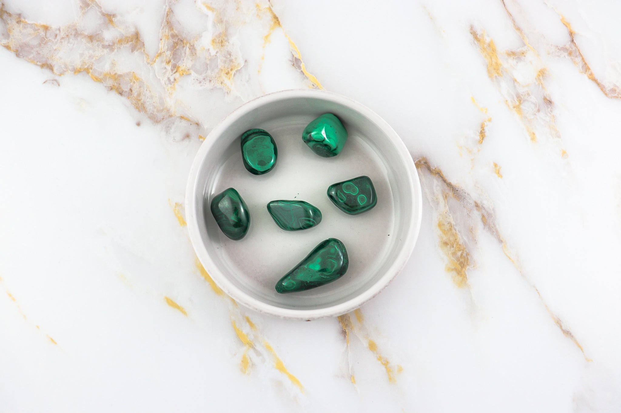 Pierre roulée en Malachite naturelle, affichant des nuances de vert clair à vert profond, idéale pour la lithothérapie.