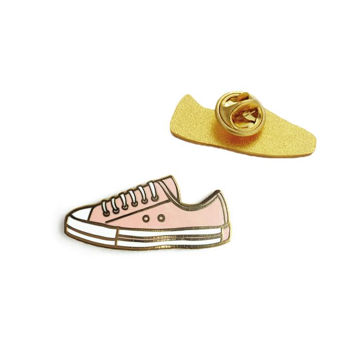 A stylish pink sneaker enamel pin with a glossy finish, perfect for fashion enthusiasts.