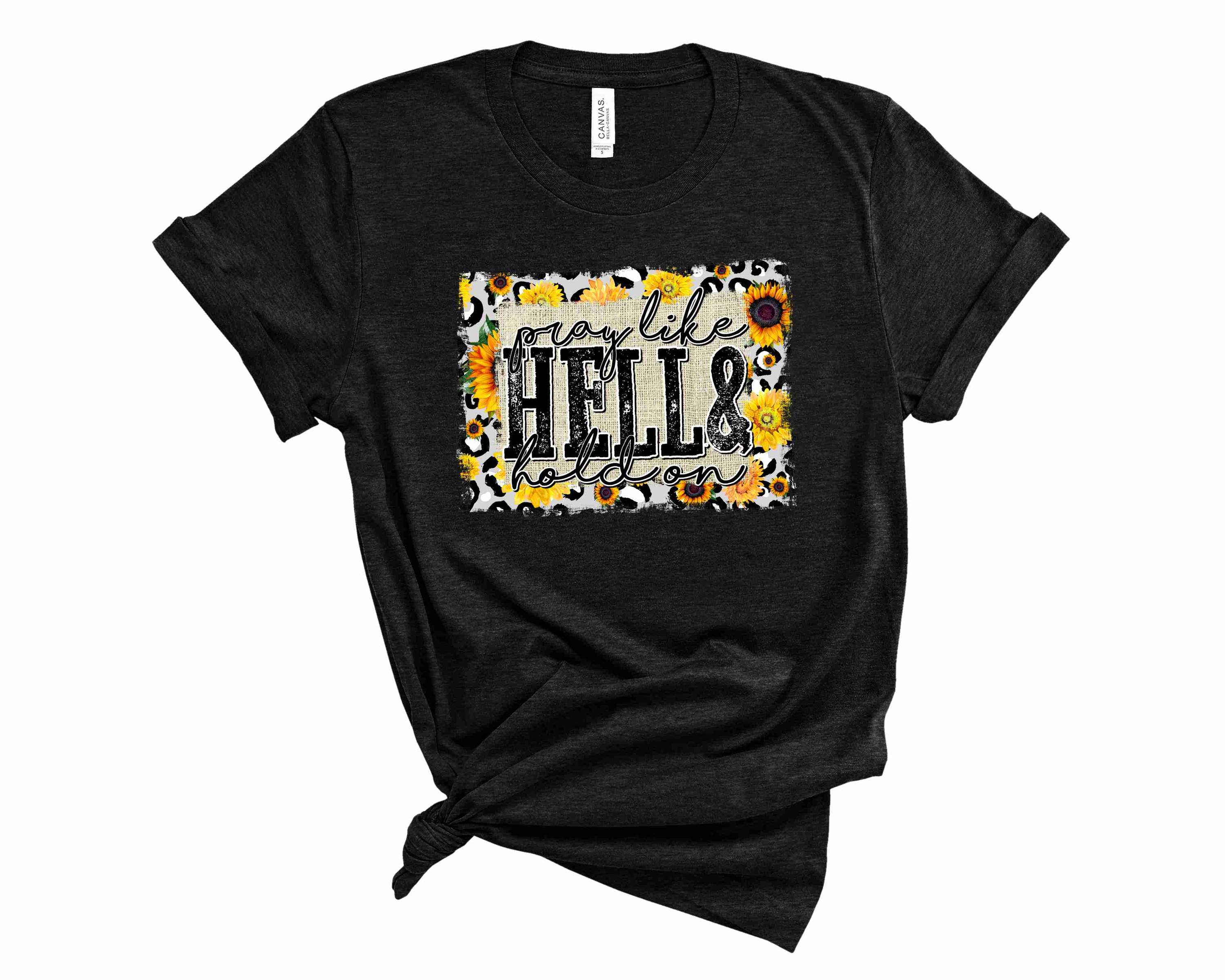 A unisex graphic t-shirt featuring the bold text 'Pray Like Hell' in a stylish design.