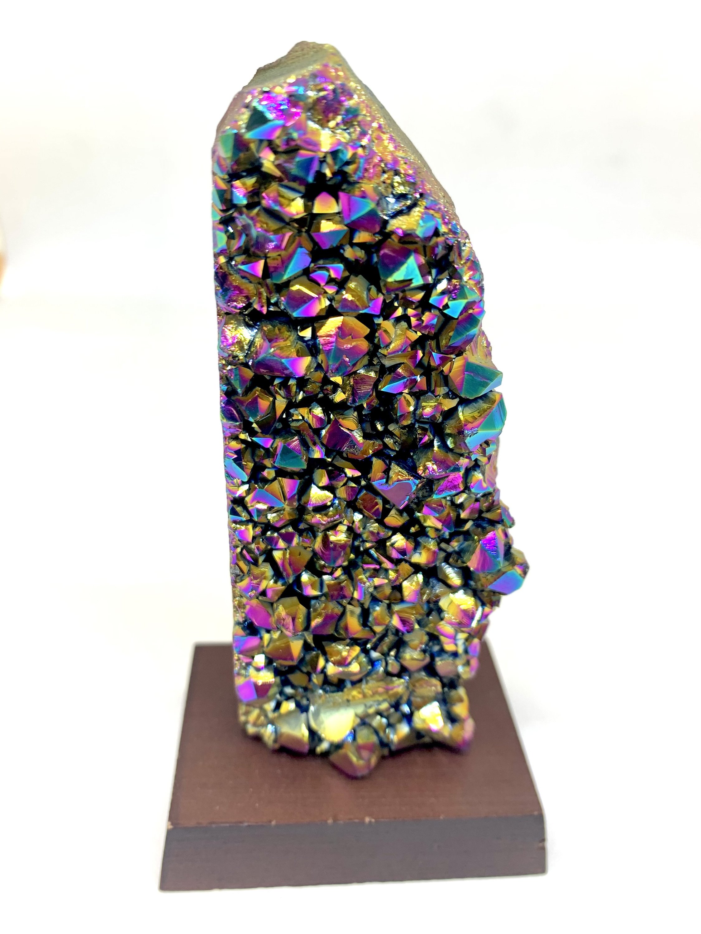 A vibrant Rainbow Amethyst Cluster showcasing shades of pink, blue, green, yellow, red, and orange, displayed on a small wooden stand.