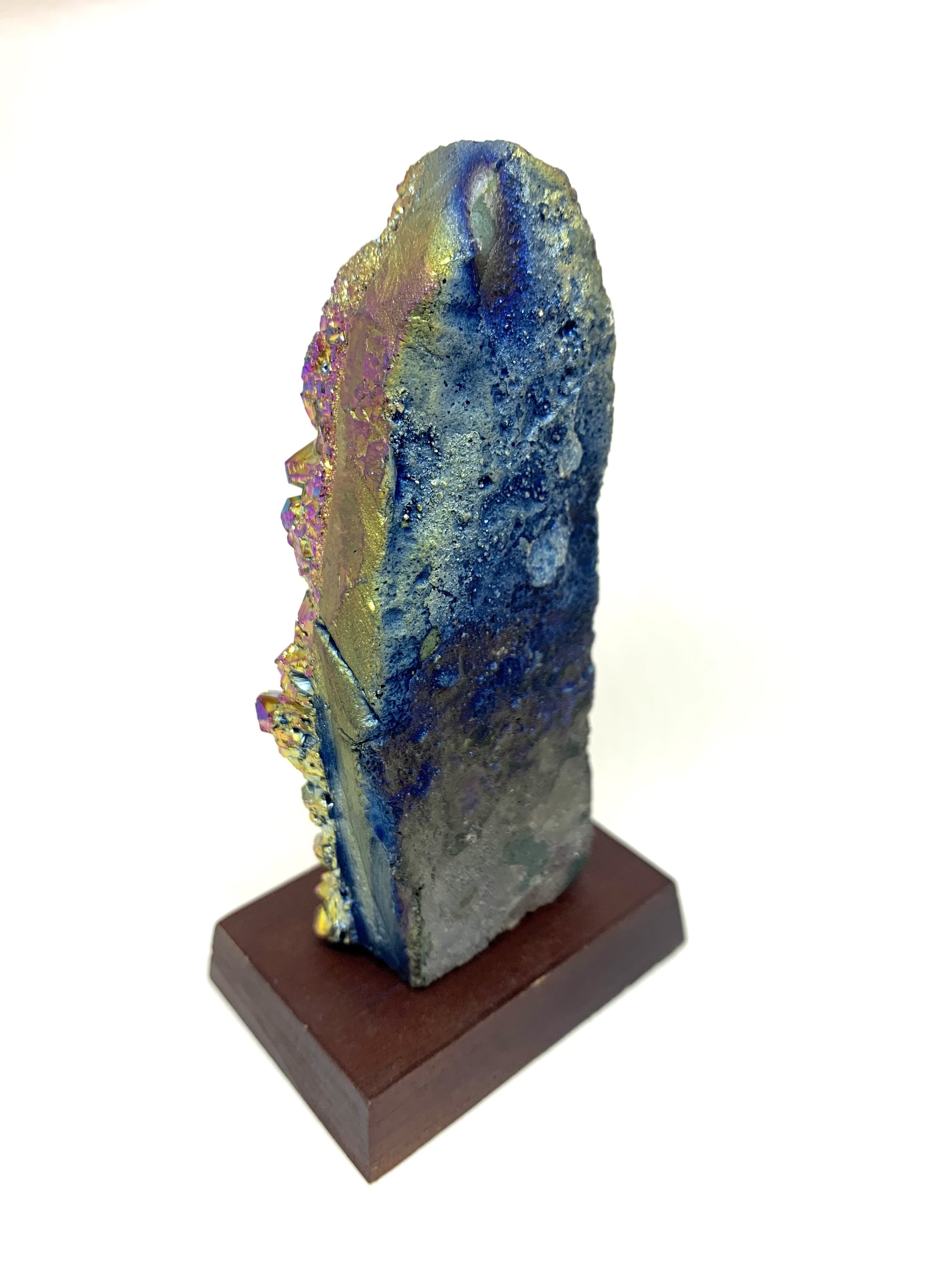 A vibrant Rainbow Amethyst Cluster showcasing shades of pink, blue, green, yellow, red, and orange, displayed on a small wooden stand.