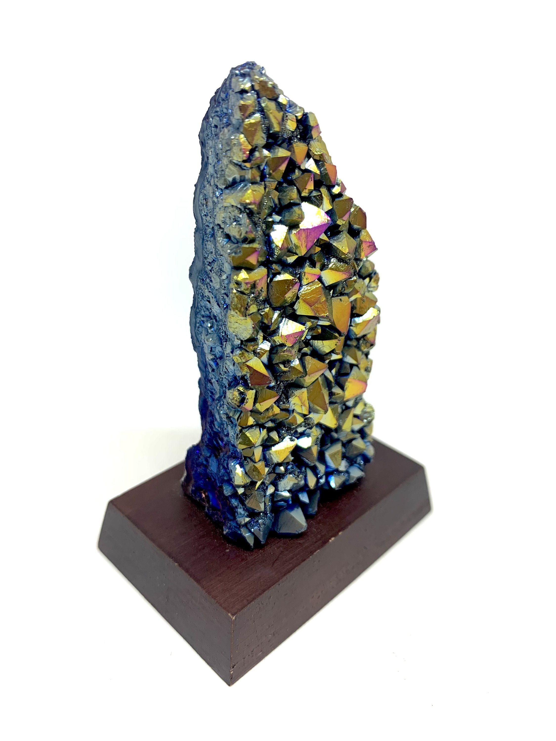 A vibrant Rainbow Amethyst Cluster showcasing shades of pink, blue, green, yellow, red, and orange, displayed on a small wooden stand.