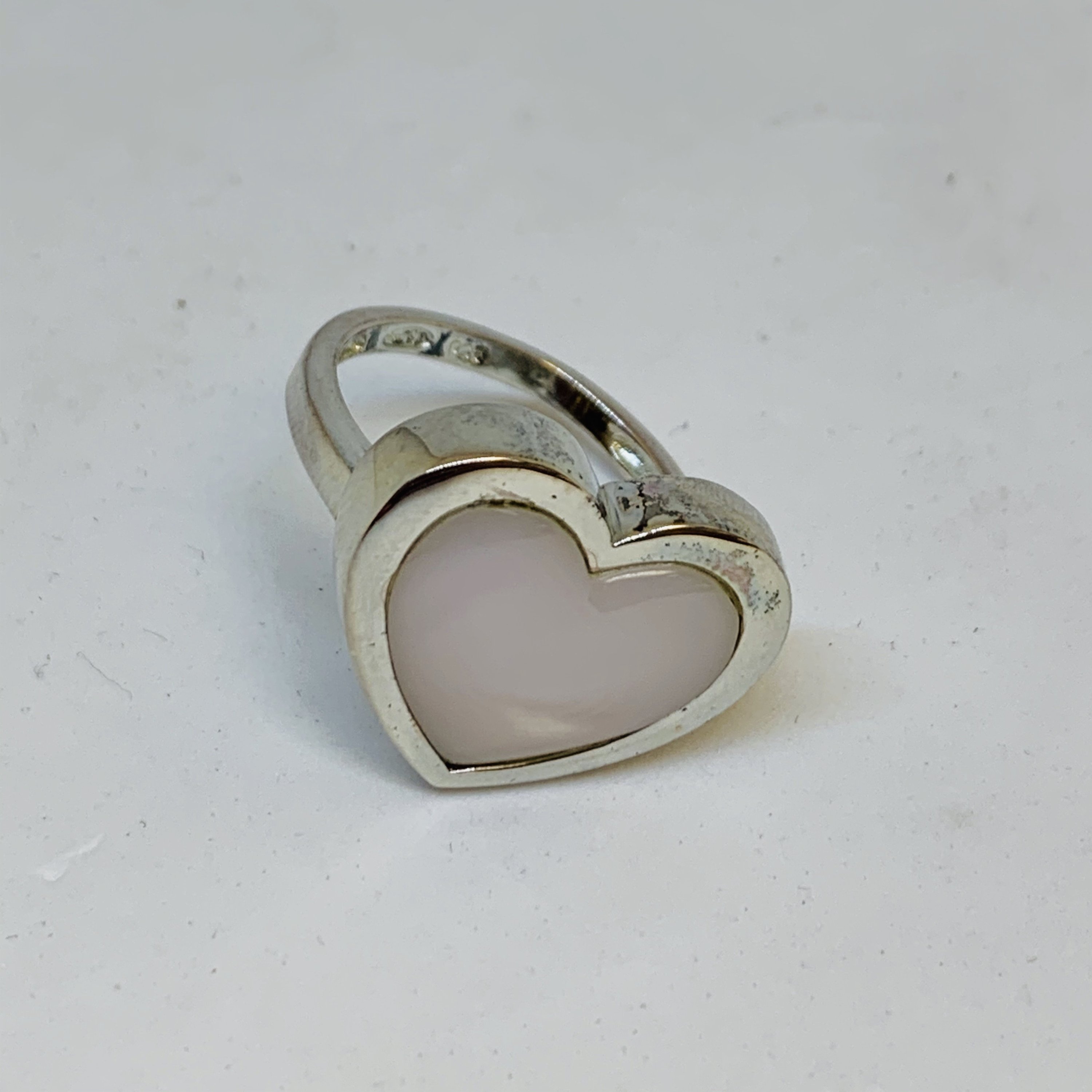 A stunning Silver Mother Of Pearl Ring featuring a heart-shaped design, crafted from 925 sterling silver, showcasing its elegant and protective qualities.
