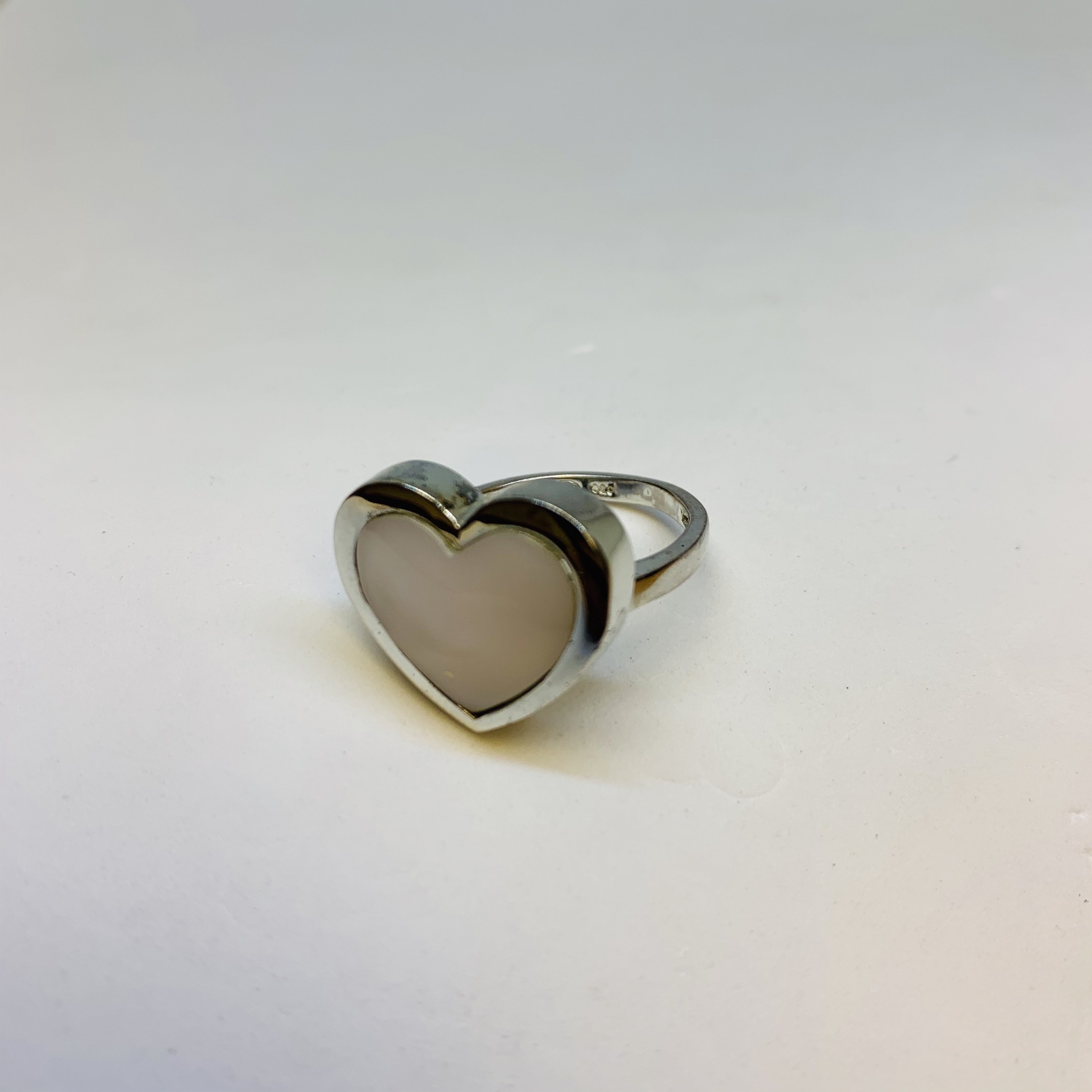 A stunning Silver Mother Of Pearl Ring featuring a heart-shaped design, crafted from 925 sterling silver, showcasing its elegant and protective qualities.