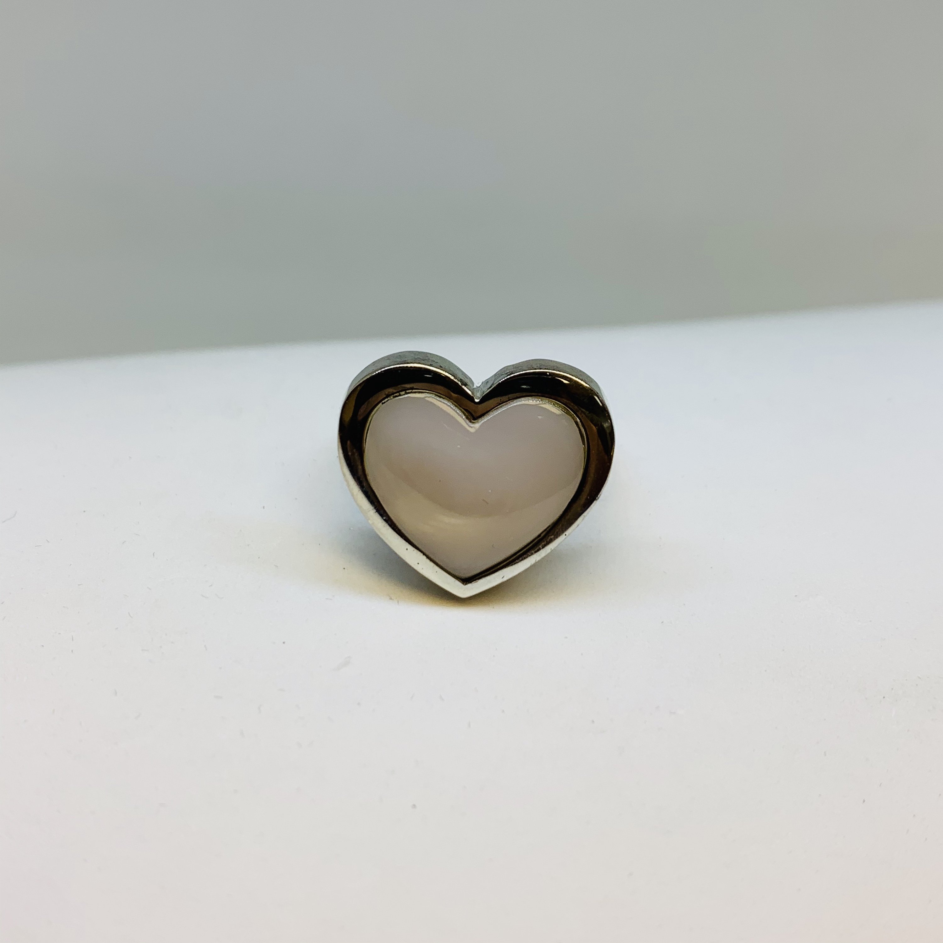 A stunning Silver Mother Of Pearl Ring featuring a heart-shaped design, crafted from 925 sterling silver, showcasing its elegant and protective qualities.