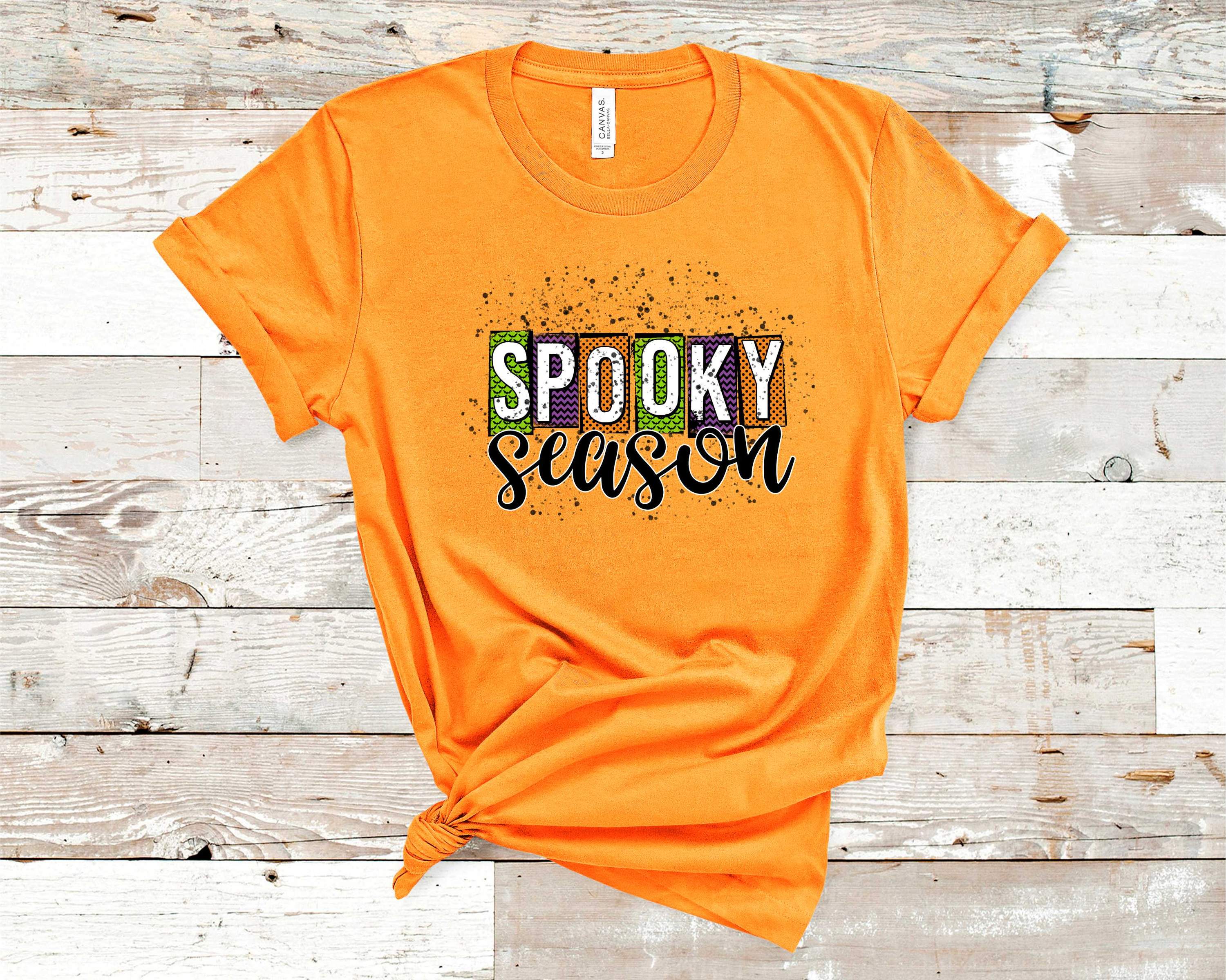 A stylish unisex graphic tee featuring a vibrant Halloween design with pumpkins and ghosts, perfect for the spooky season.