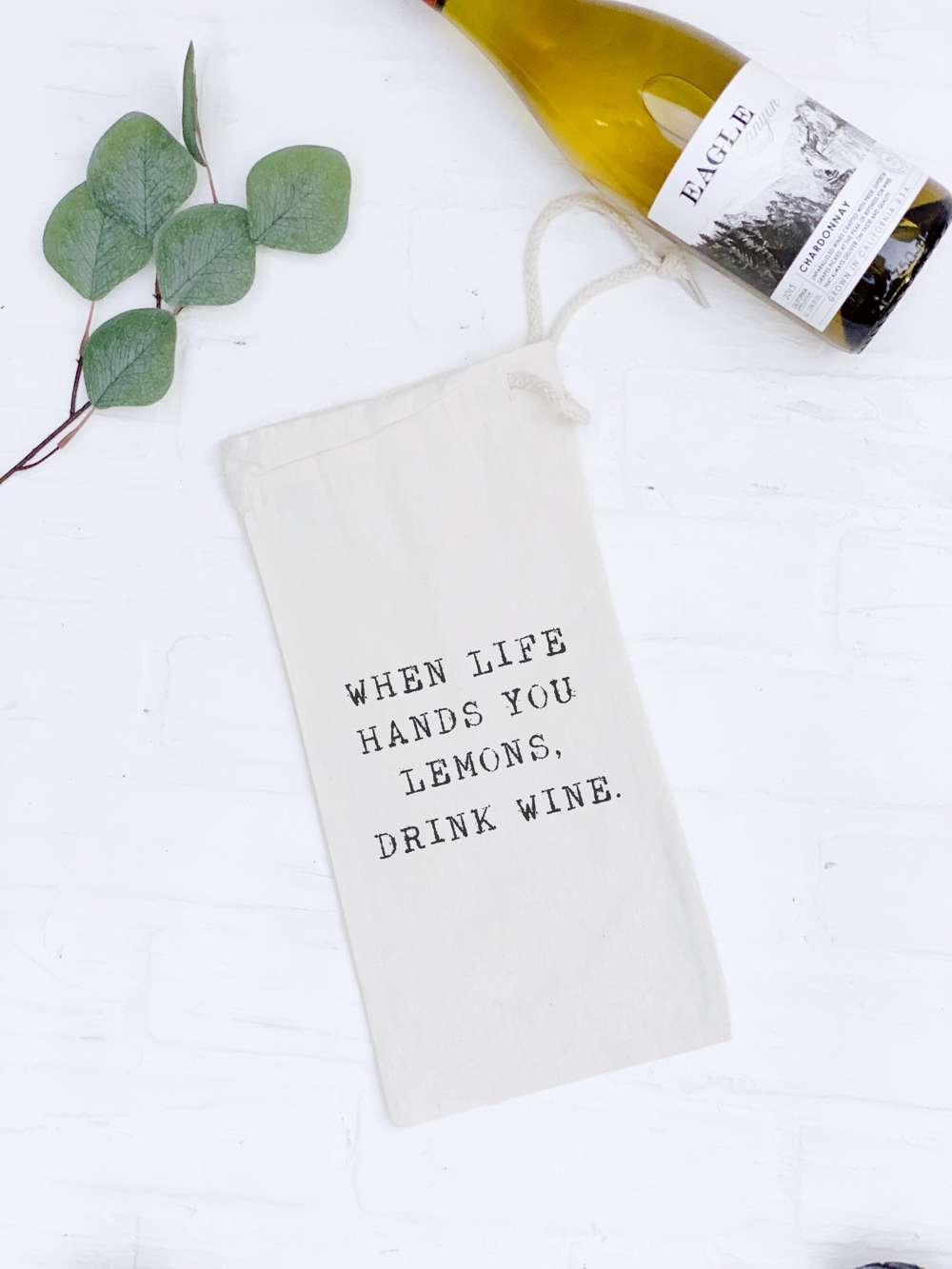 A stylish canvas wine bag with a drawstring closure, featuring a fun lemon-themed design, perfect for carrying a 750mL wine bottle.