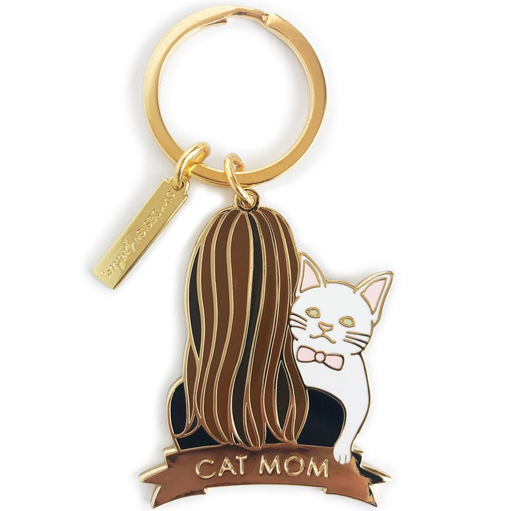 A charming white cat keychain featuring brunette hair, crafted from high-quality hard enamel, presented on a stylish backing card.