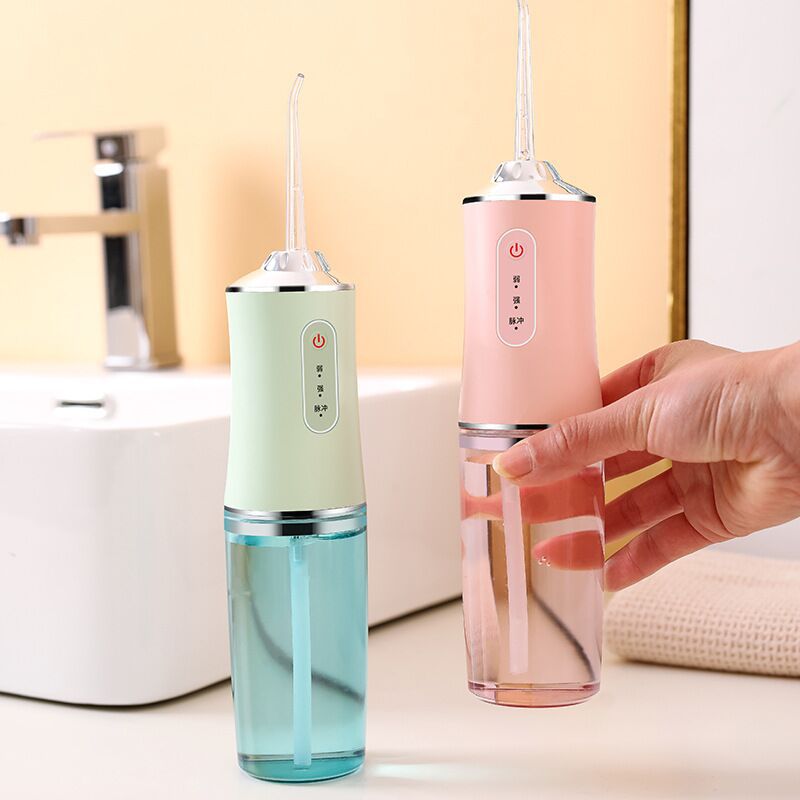 Portable 3 Modes Oral Irrigator in white, pink, and light green colors, showcasing its USB charging feature and compact design.