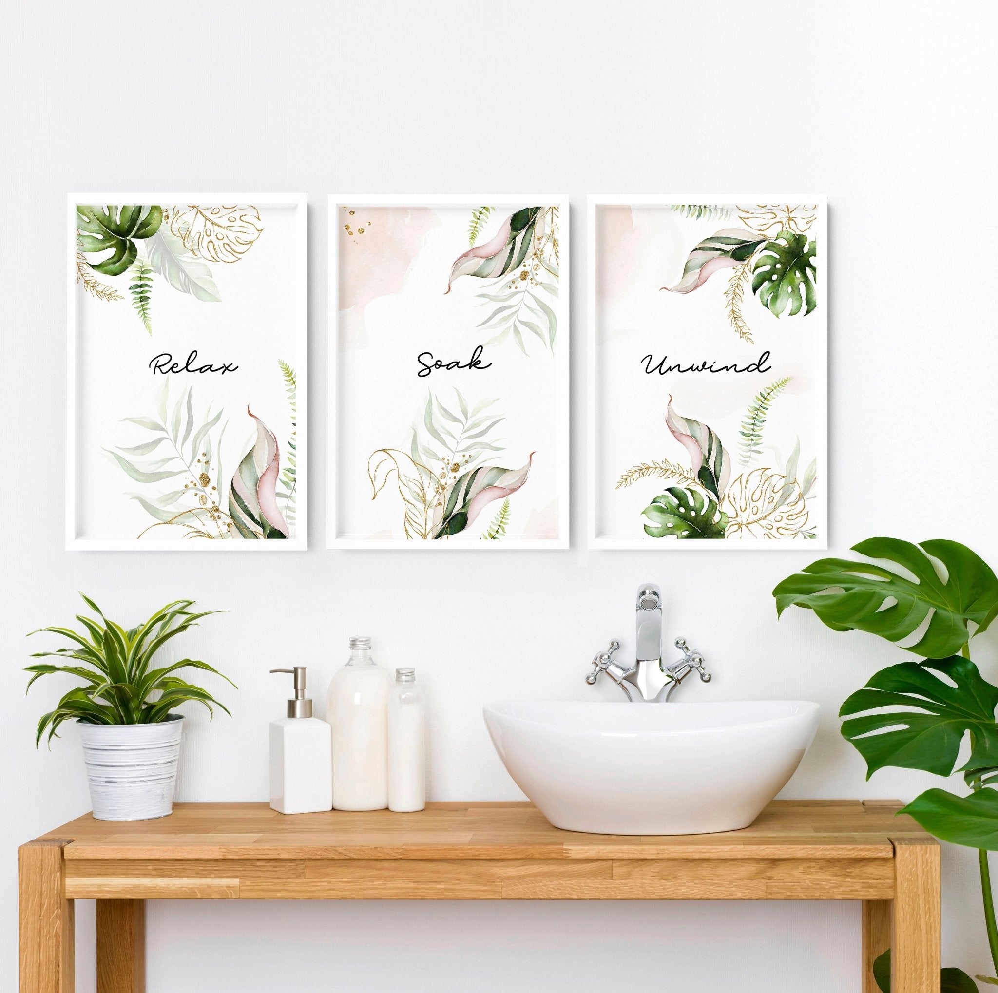 Set of 3 tropical wall art prints featuring palm leaves and exotic flowers in soft green, pink, and gold colors, perfect for bathroom decor.
