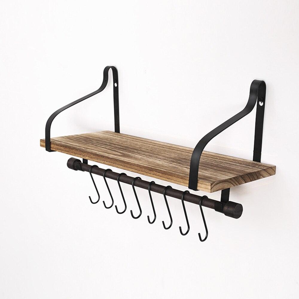 Rustic wood wall shelf mounted in a kitchen, featuring a wooden board, metal brackets, and hooks for coffee cups and towels.