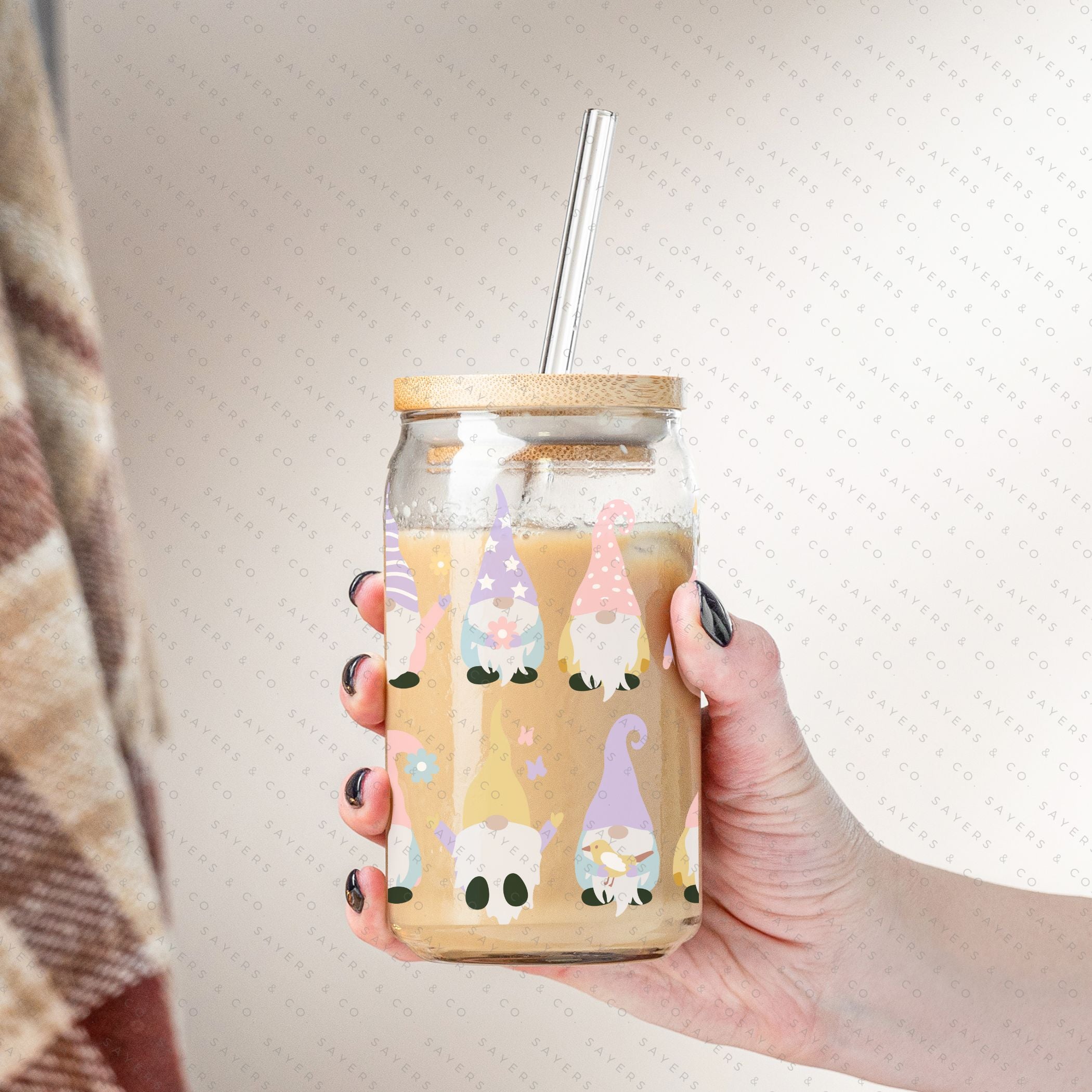 A 16oz clear glass cup featuring a whimsical spring gnome design, complete with a bamboo lid and a clear plastic straw, perfect for various beverages.