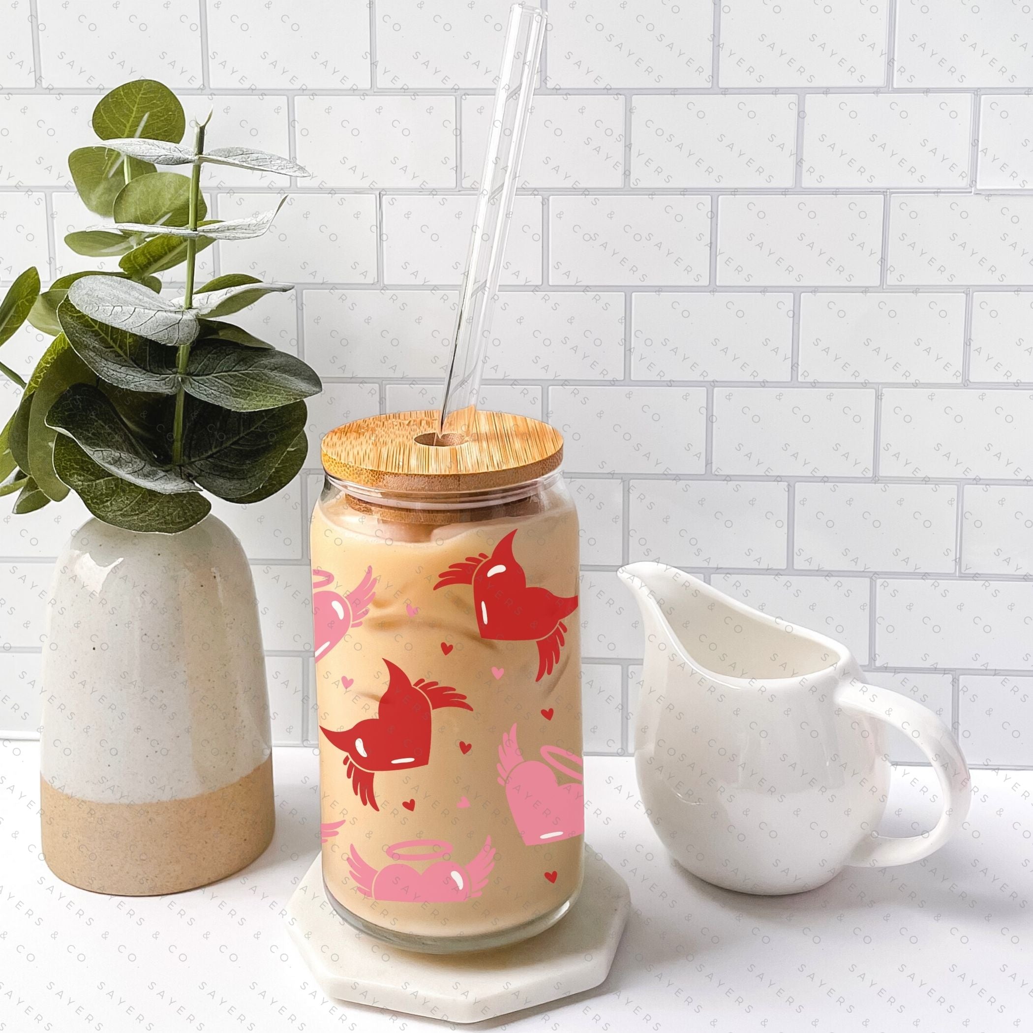 16oz Valentine's Day glass cup featuring angel and devil hearts design, with bamboo lid and clear straw, perfect for beverages.