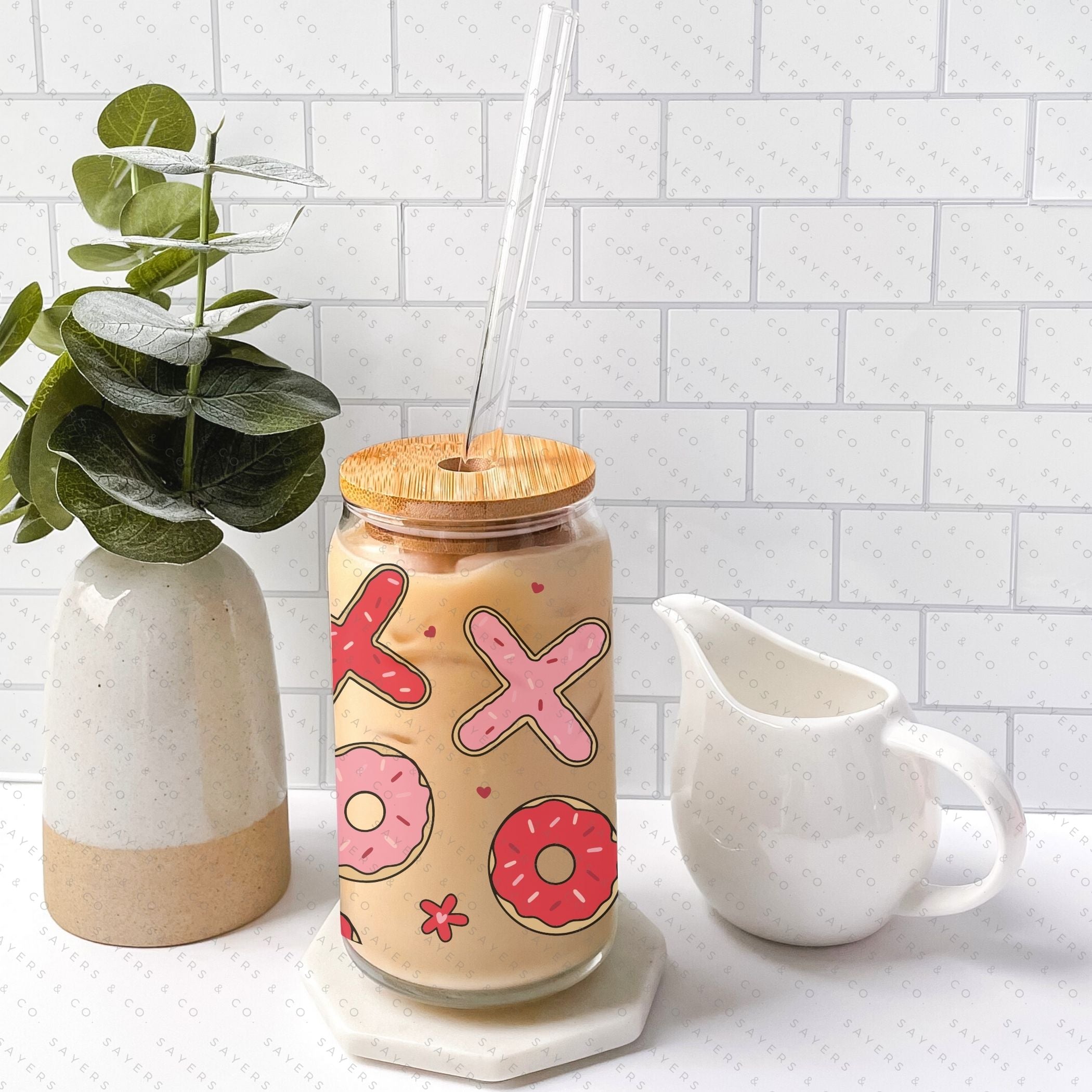 16oz Valentine's Day Xs and Os Donut Glass Cup featuring a bamboo lid and straw, perfect for drinks.