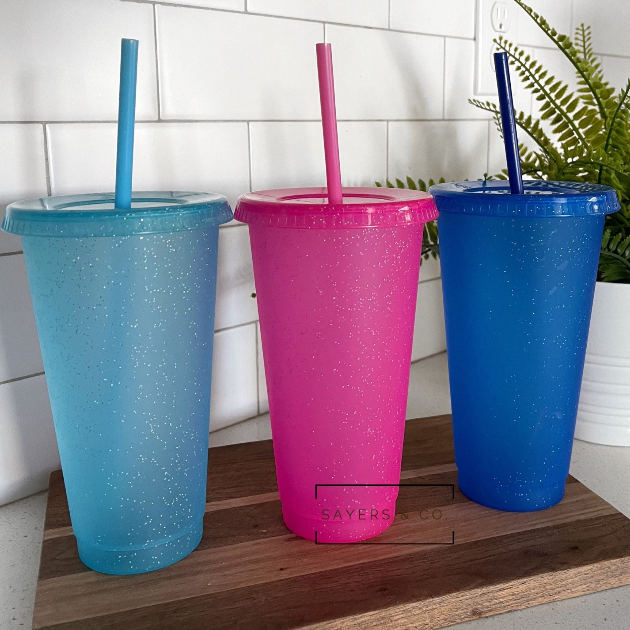 24oz Matte Glitter Cold Cup in aqua, pink, and blue glitter options, alongside a matte black version, with matching straw and lid.