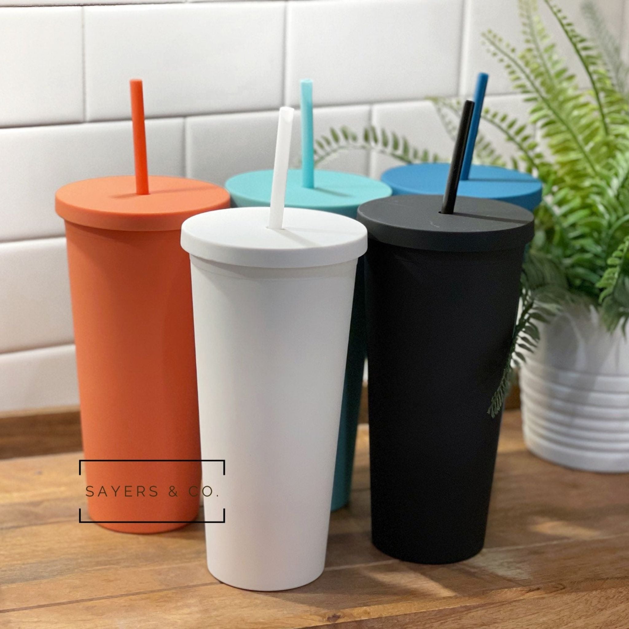 A 22oz Acrylic Matte Colored Double Walled Tumbler in various colors with a screwtop lid and matching straw, showcasing its stylish design.