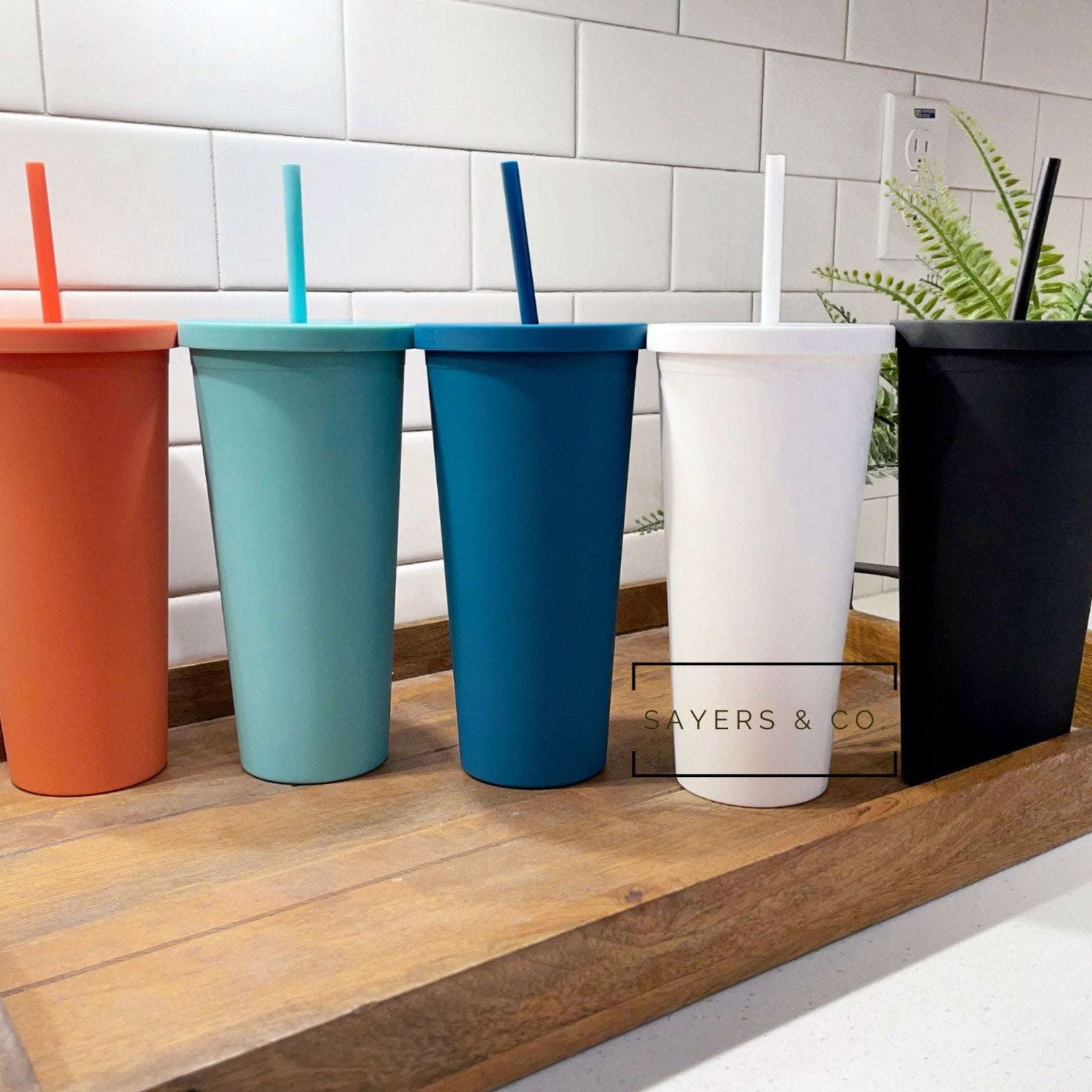 A 22oz Acrylic Matte Colored Double Walled Tumbler in various colors with a screwtop lid and matching straw, showcasing its stylish design.