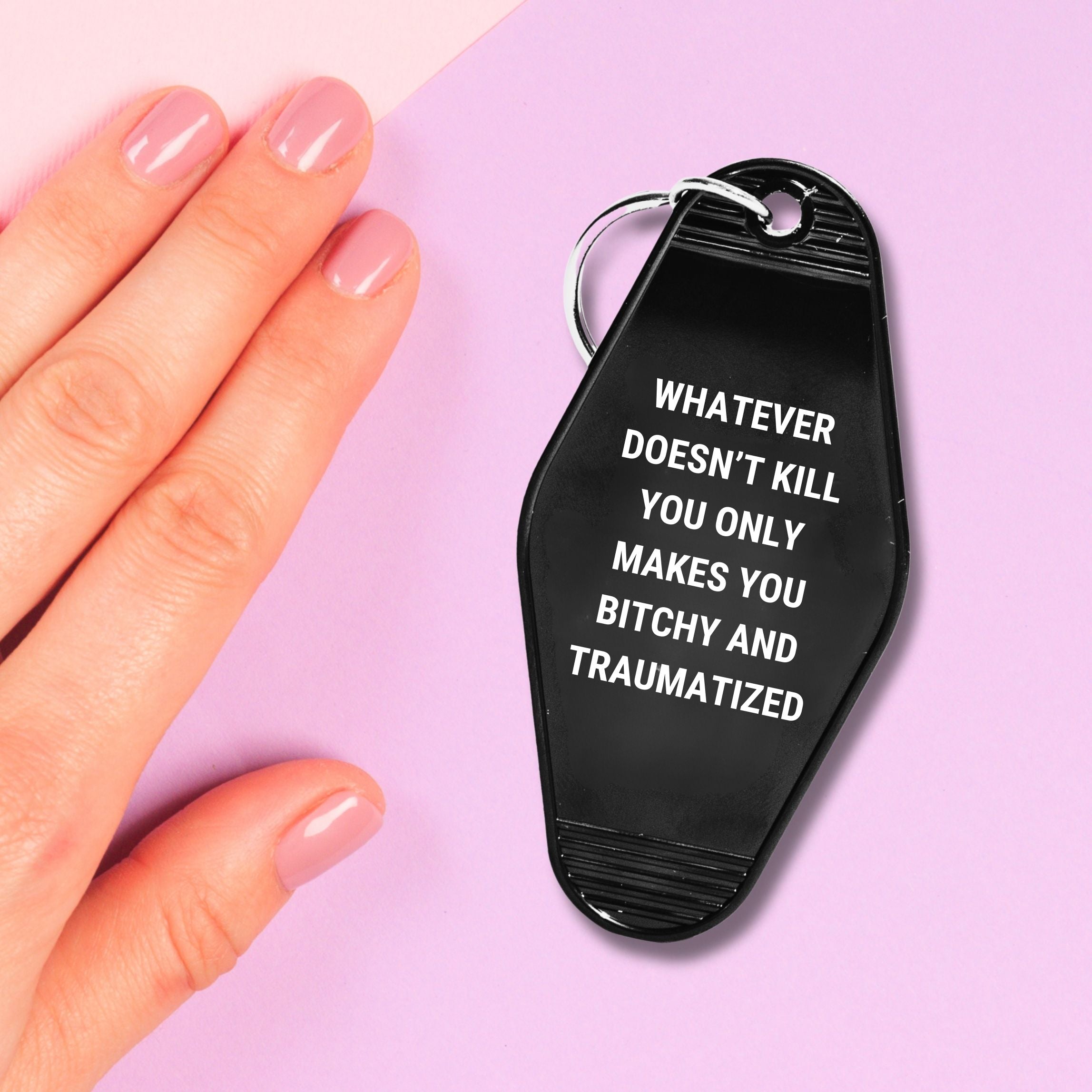 A humorous motel keychain featuring the phrase 'Whatever Doesn’t Kill You Only Makes You Bitchy And Traumatized' with a split ring attachment.