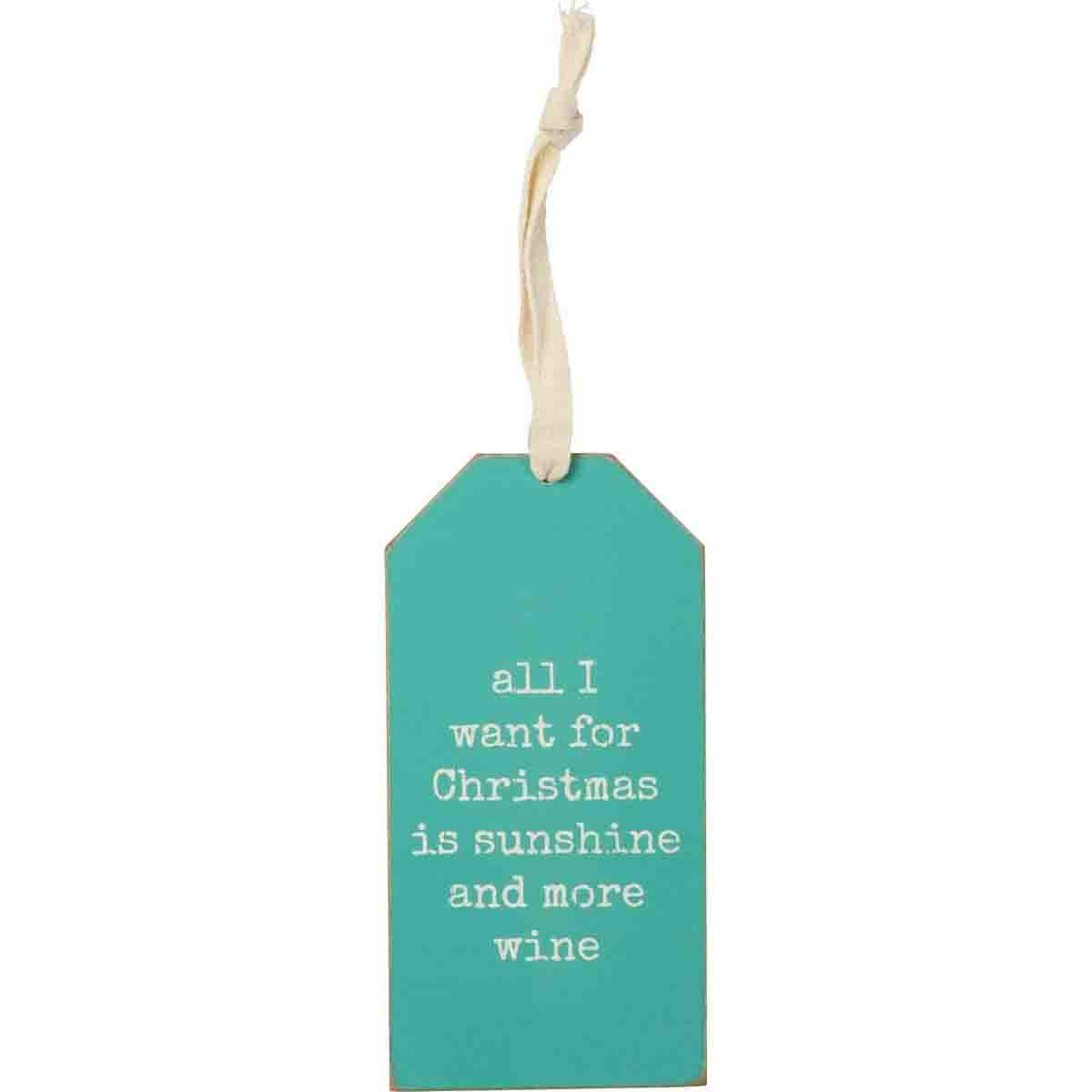Wooden bottle tag with beach-themed Christmas design, featuring the phrase 'All I Want For Christmas Is Sunshine And More Wine' and a fabric loop.