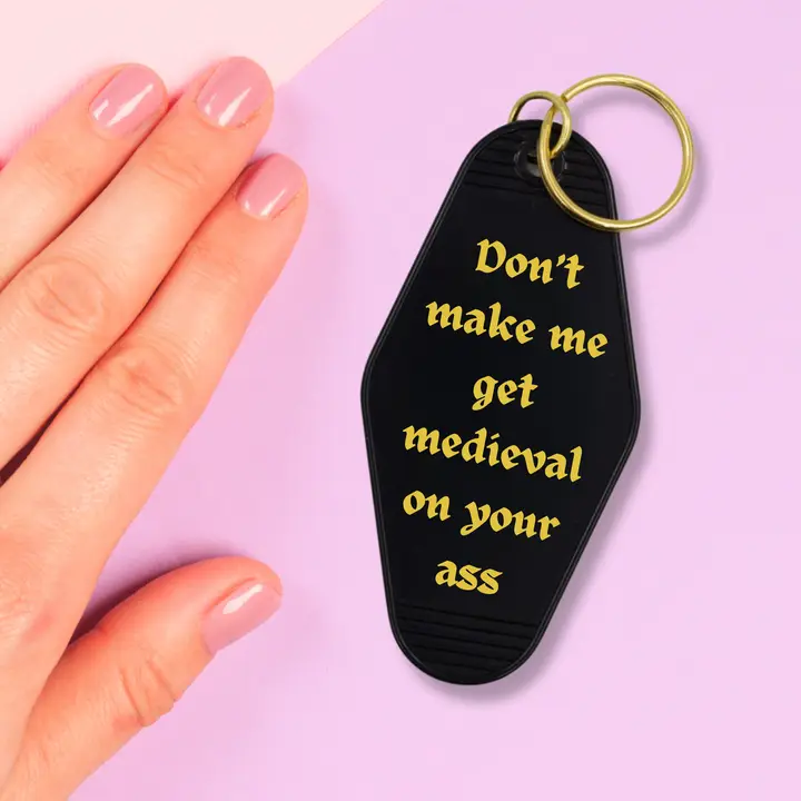 A humorous motel-style keychain featuring the phrase 'Don't make me get medieval on your ass', designed in a classic hotel key tag style.