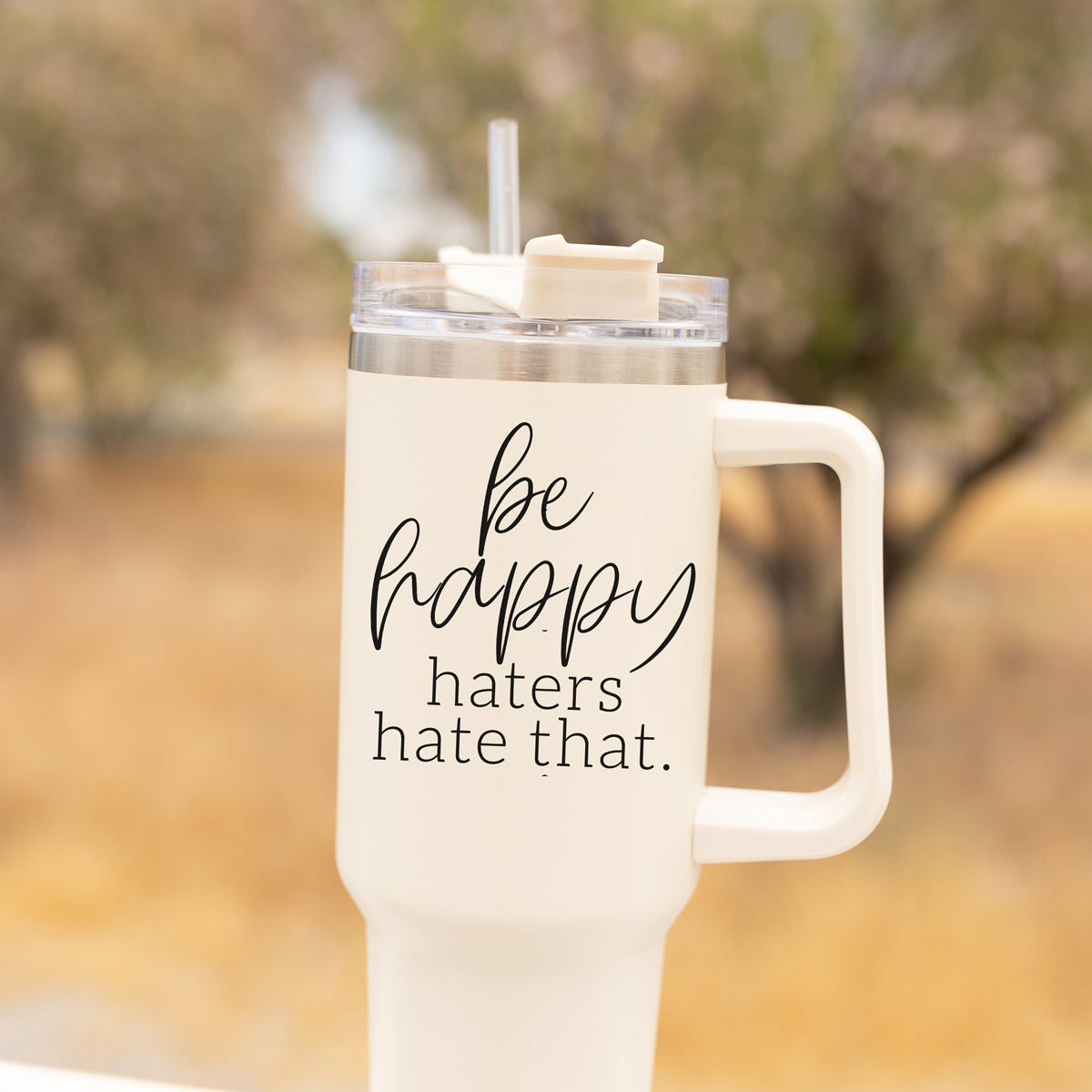 Be Happy 40oz insulated mug with handle, lid, and straw, featuring a matte cream finish and black graphic design.