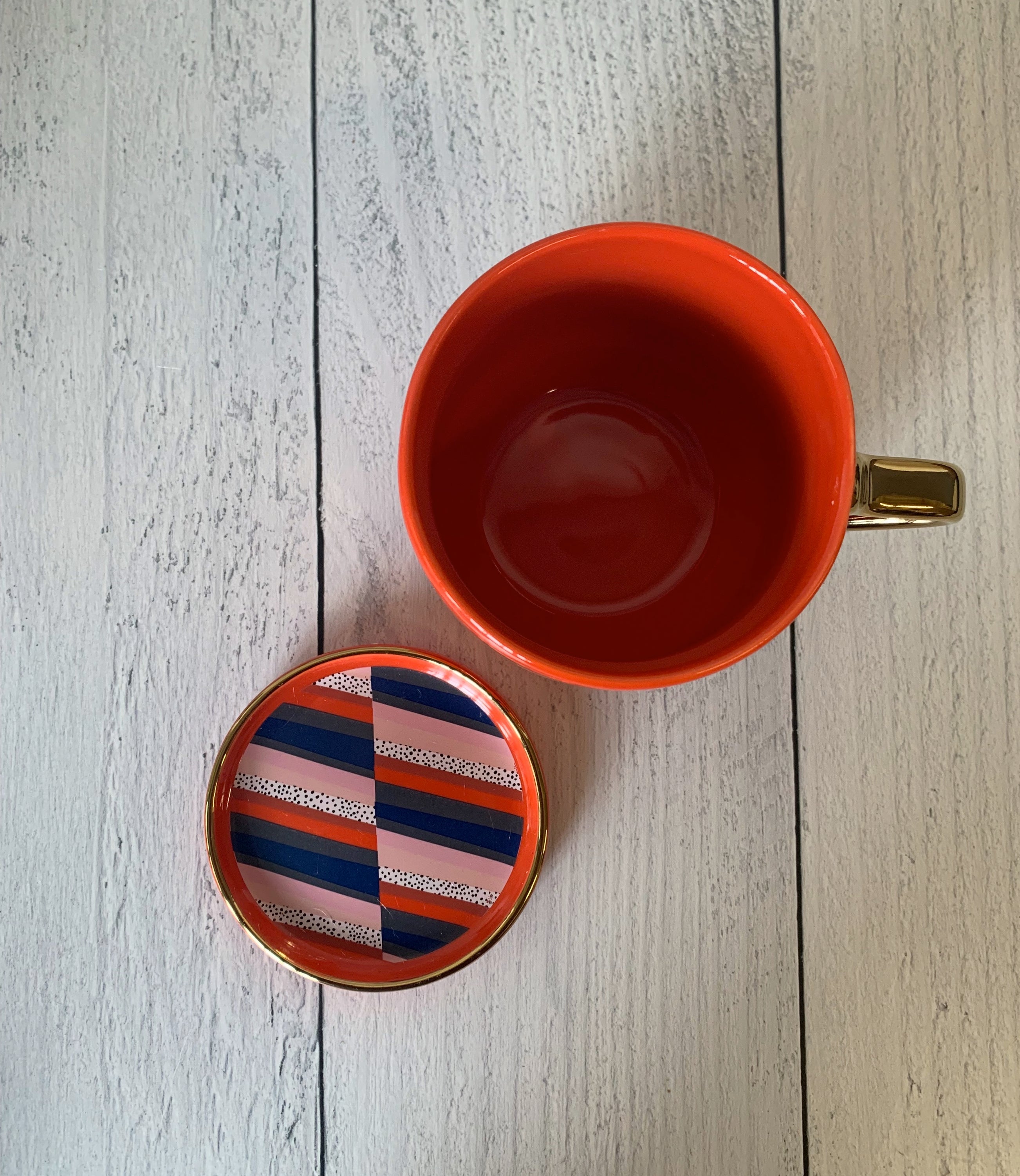 A stylish red and gold ceramic mug with 'BOSSY' printed on it, accompanied by a matching coaster lid.