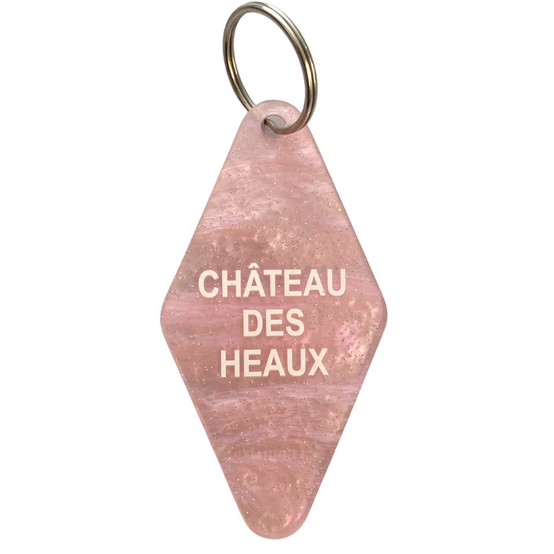 Chateau Des Heaux Motel Style Keychain in Crystal Pink with white lettering, featuring a split ring for key attachment.